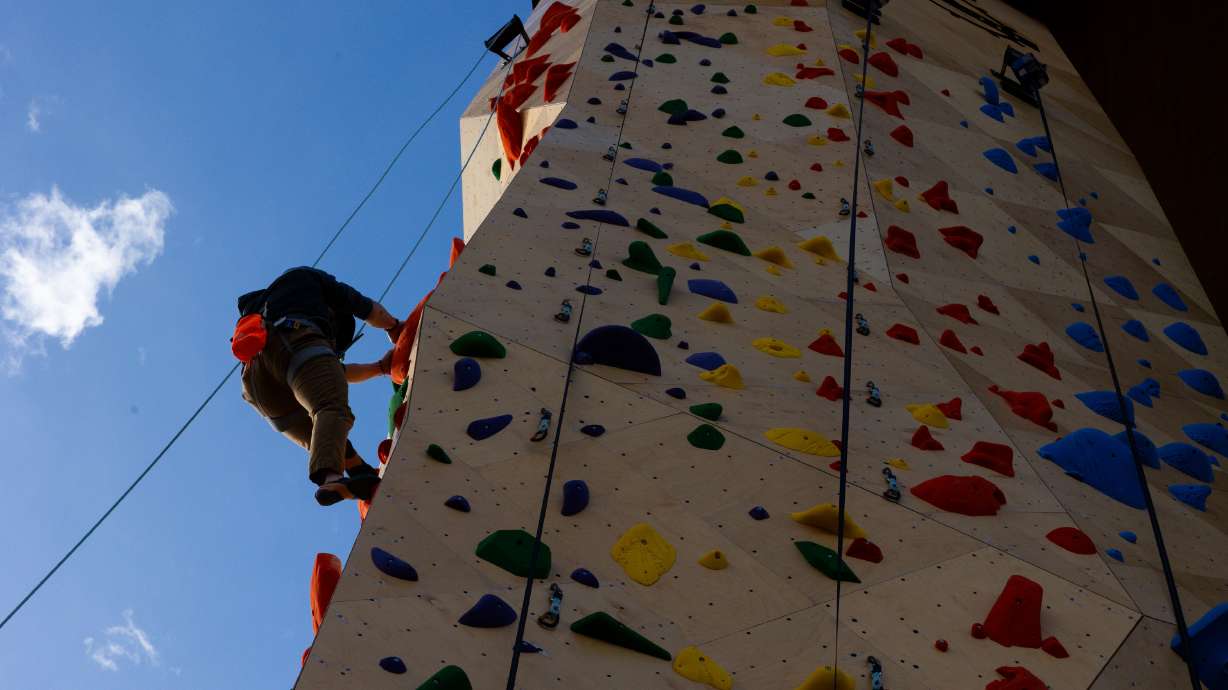 Attendees climb at the grand opening of an outdoor climbing wall outside of Millcreek City Hall on Saturday — possibly the world’s first “city hall climbing wall.”