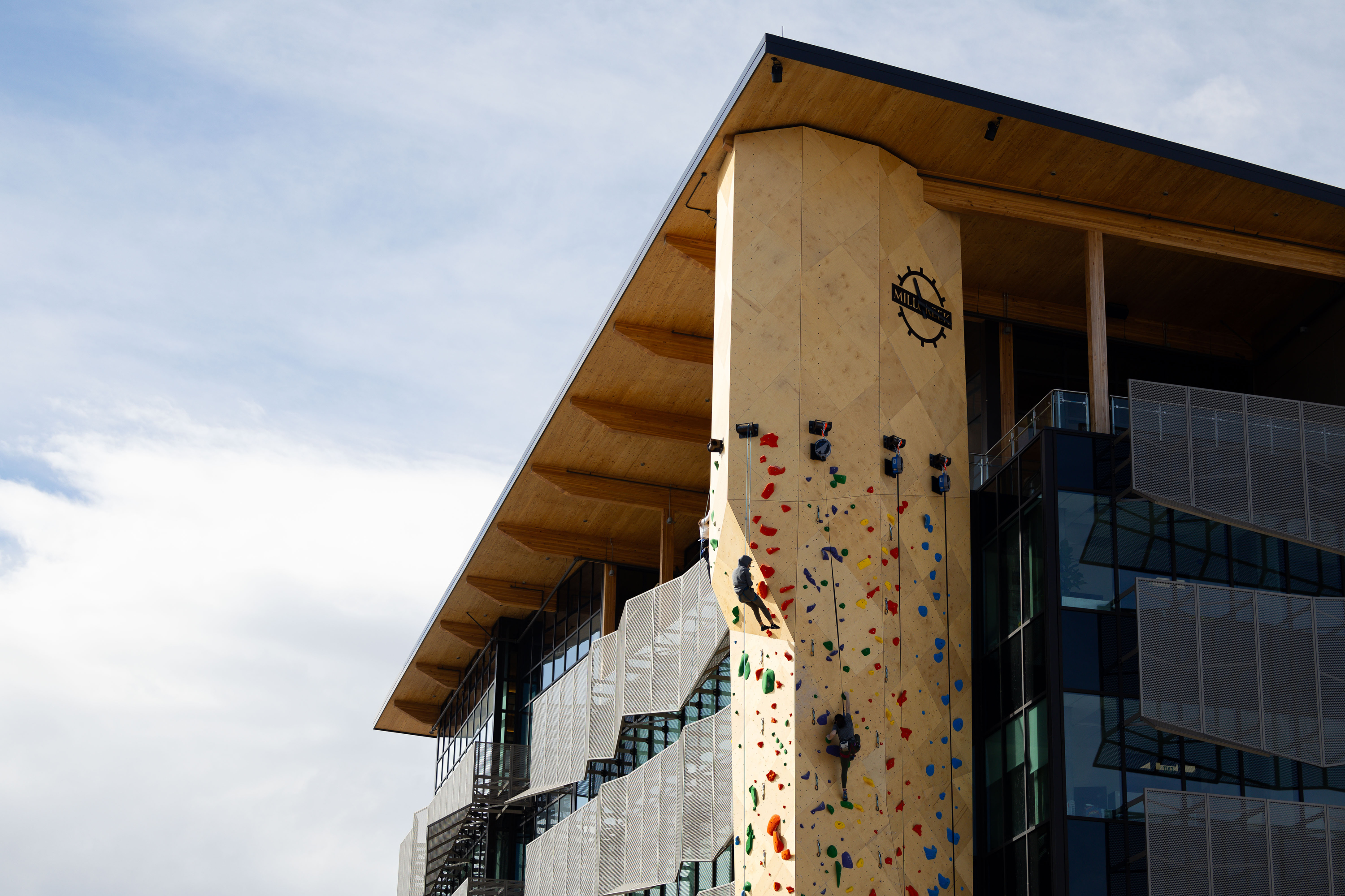 Attendees climb at the grand opening of an outdoor climbing wall outside Millcreek City Hall on Saturday.
