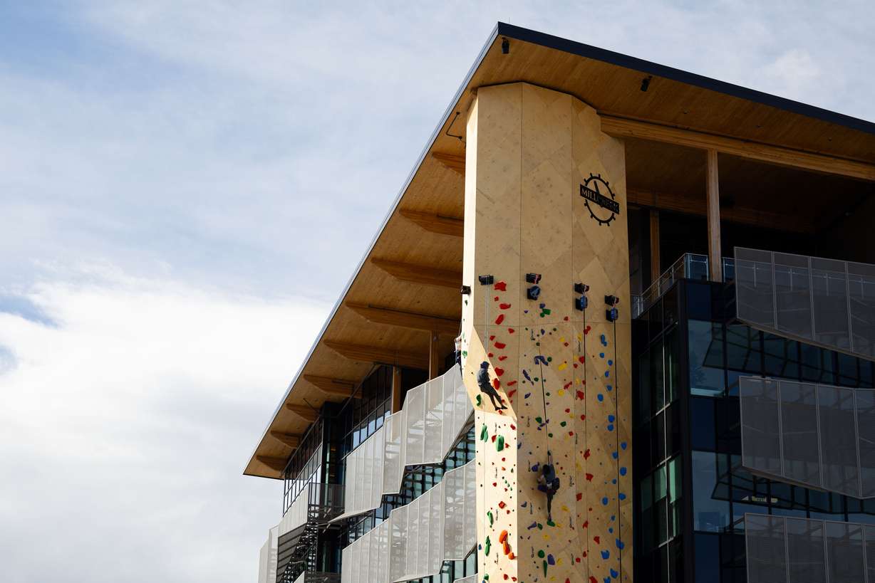 Attendees climb at the grand opening of an outdoor climbing wall outside Millcreek City Hall on Saturday.
