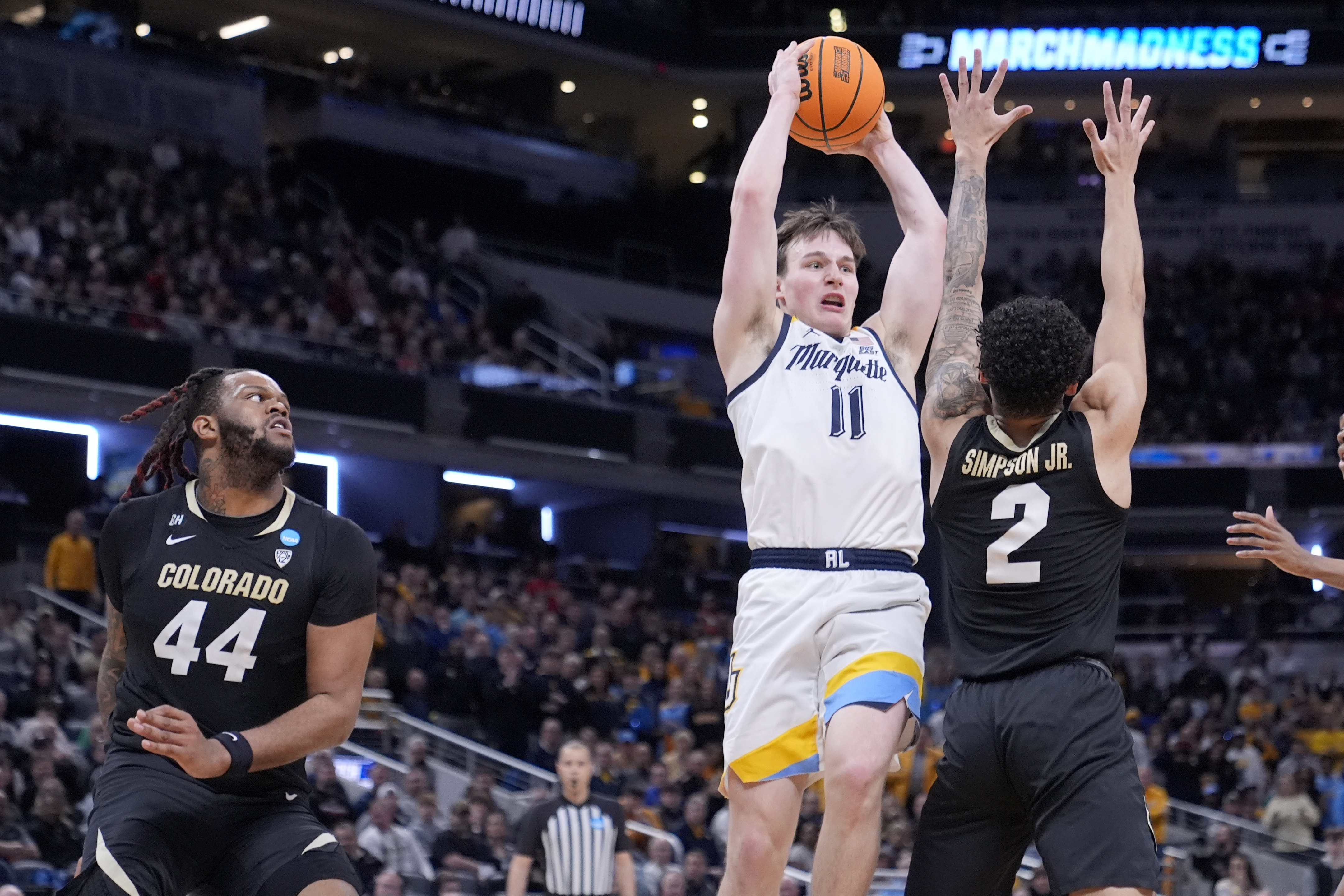 Marquette's Tyler Kolek (11) tries to pass over Colorado's KJ Simpson (2) as Colorado's Eddie Lampkin Jr. (44) watches during the first half of a second-round college basketball game in the NCAA Tournament, Sunday, March 24, 2024 in Indianapolis.