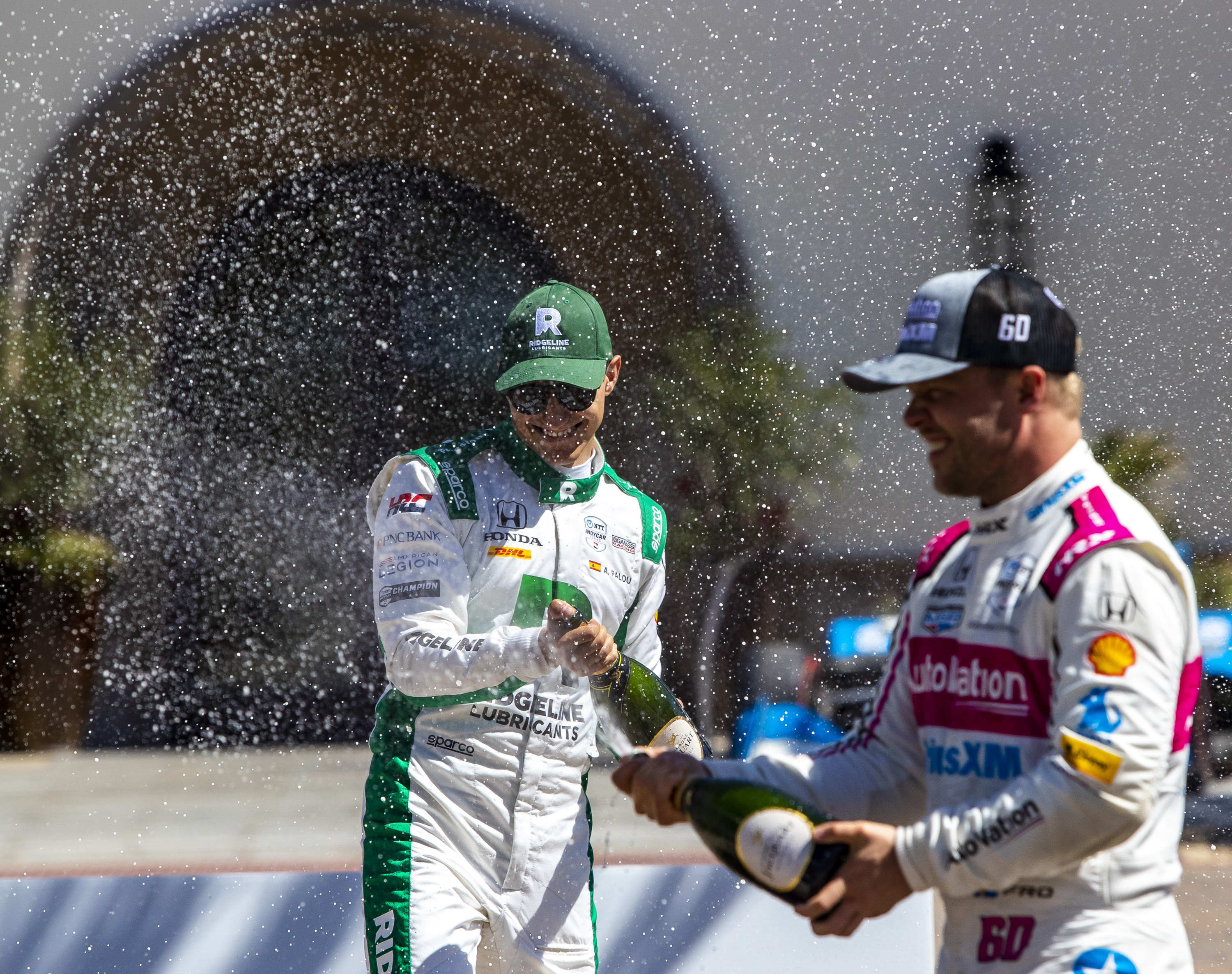 Winner Alex Palou, left, of Chip Ganassi Racing, celebrates with third-place finisher Felix Rosenqvist, right, of Meyer Shank Racing, after the featured auto race of the Thermal $1 Million Challenge with his team at The Thermal Club in Thermal, Calif., Sunday, March 24, 2024.