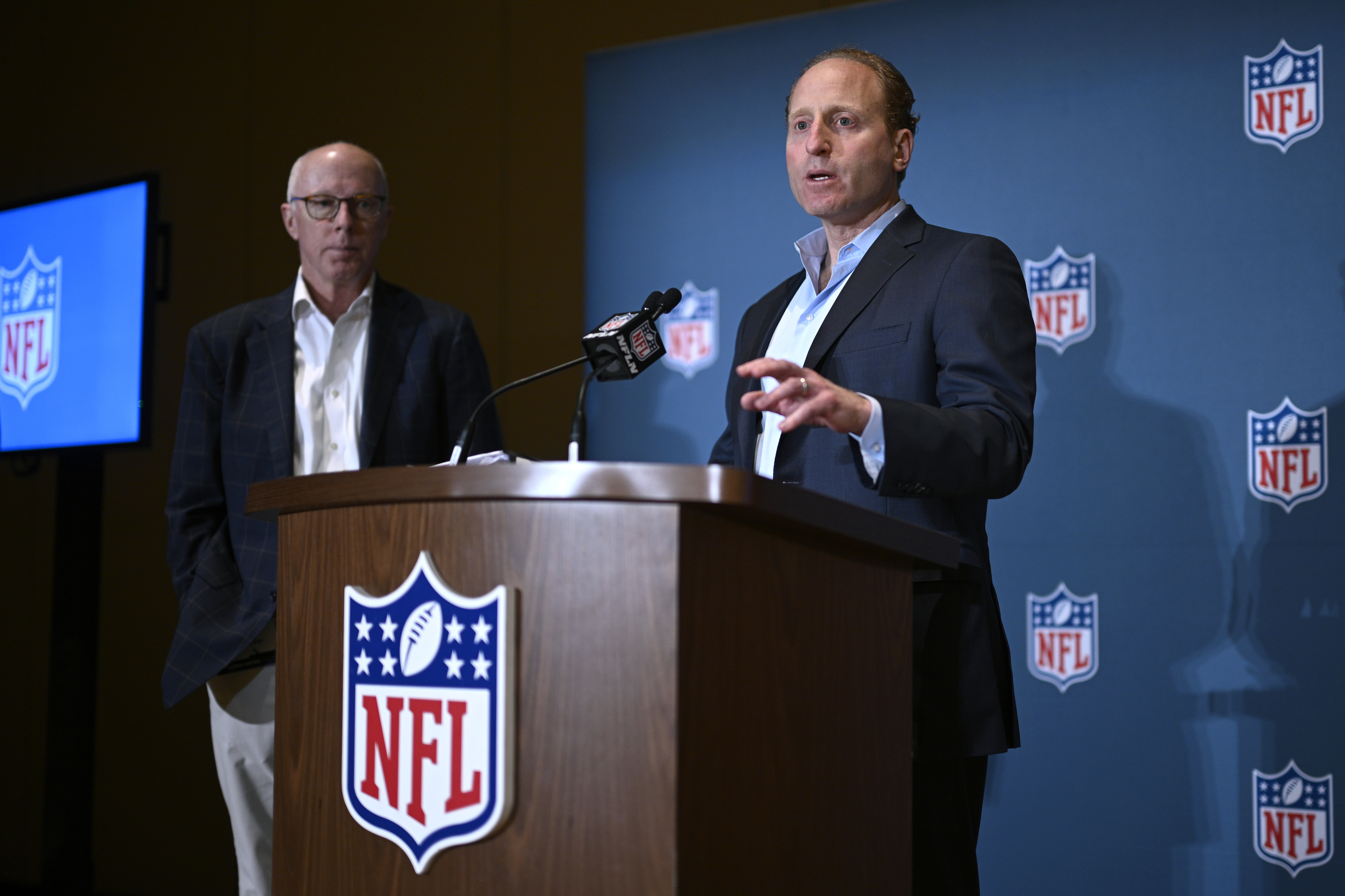 Rich McKay, left, Atlanta Falcons CEO and Competition Committee Chairman, looks on as Jeff Miller, NFL Executive Vice President of Communications, addresses reporters about rules changes at the NFL owners meetings, Monday, March 25, 2024, in Orlando, Fla.