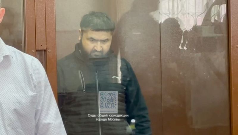 Alisher Kasimov, a suspect in the Crocus City Hall attack charged with providing accommodation to the four men accused of carrying out shooting in the concert hall, sits behind a glass wall of an enclosure for defendants in a courtroom in Moscow, Russia, Tuesday.