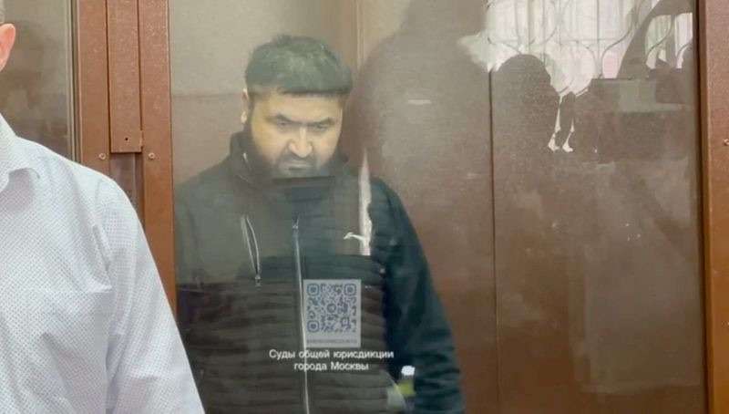 Alisher Kasimov, a suspect in the Crocus City Hall attack charged with providing accommodation to the four men accused of carrying out shooting in the concert hall, sits behind a glass wall of an enclosure for defendants in a courtroom in Moscow, Russia, Tuesday.