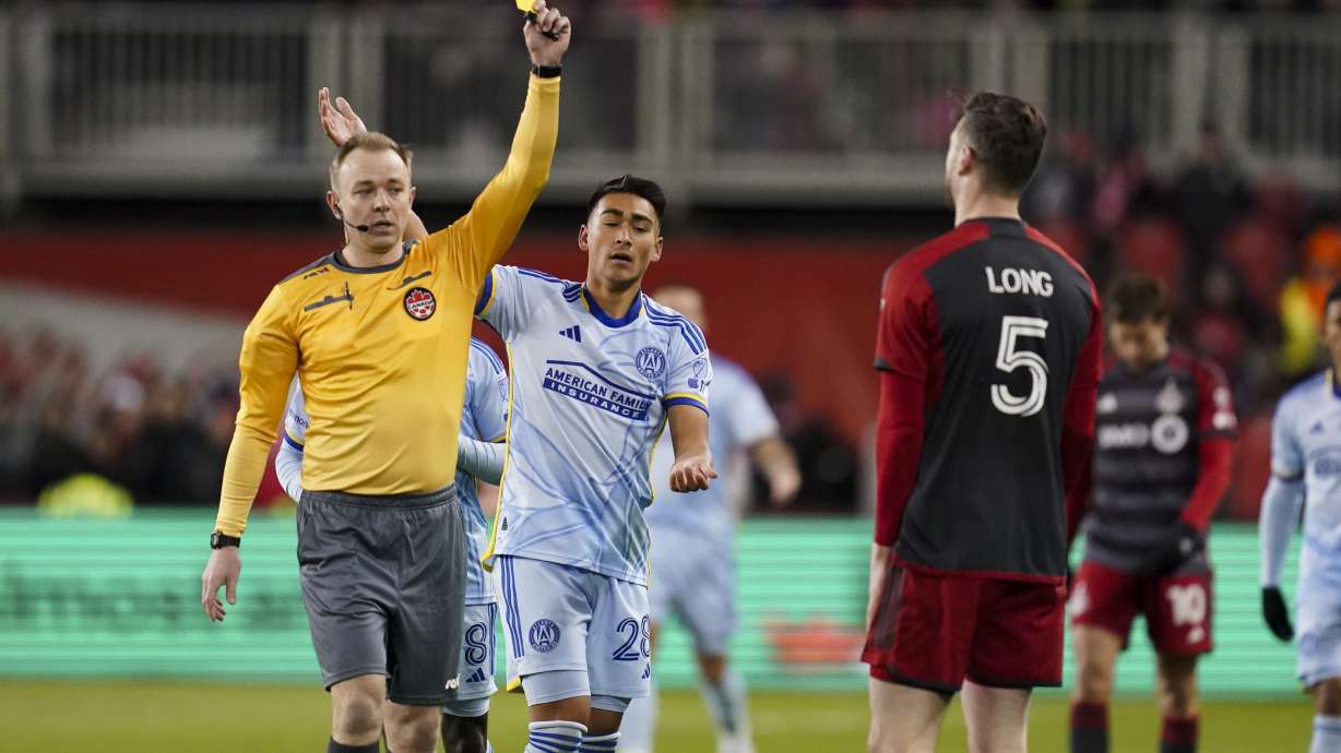 Referee Scott Bowman, left, shows a yellow card to Toronto FC defender Kevin Long (5) while Atlanta United forward Tyler Wolff (28) looks on during first-half MLS soccer match action in Toronto, Saturday, March 23, 2024.