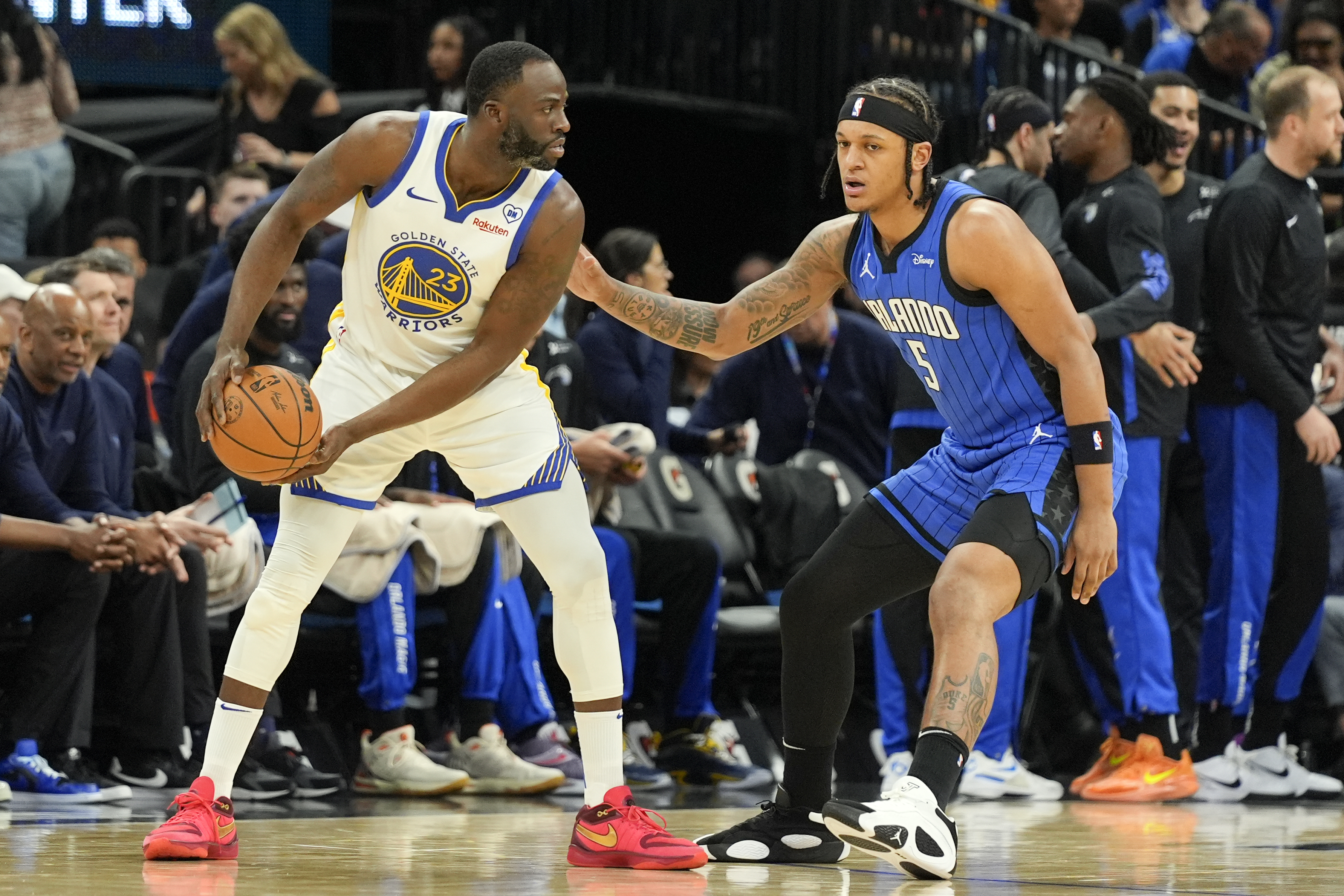 Golden State Warriors forward Draymond Green (23) looks for an opening as Orlando Magic forward Paolo Banchero (5) defends during the first half of an NBA basketball game Wednesday, March 27, 2024, in Orlando, Fla.
