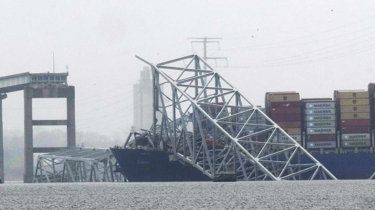 A container ship rests against the wreckage of the Francis Scott Key Bridge on Thursday, in Baltimore, Md. The largest crane on the Eastern Seaboard is arriving by barge so crews can begin removing the wreckage from the deadly bridge collapse.