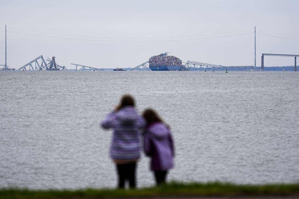 People view from Fort McHenry a container ship as it rests against the wreckage of the Francis Scott Key Bridge, Thursday, in Baltimore.