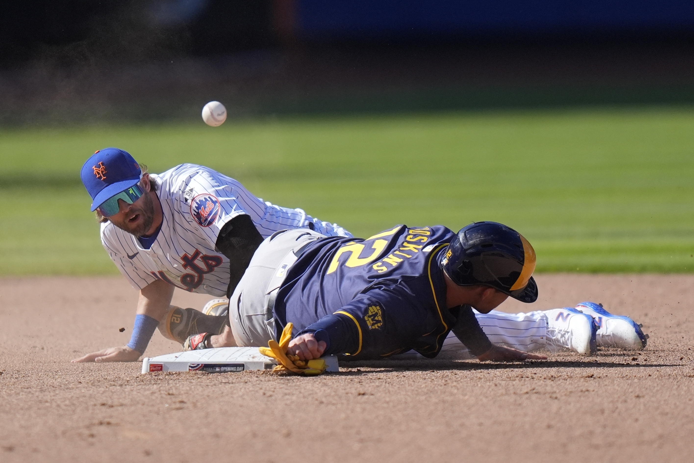 New York Mets' Jeff McNeil (1) loses control of the ball as Milwaukee Brewers' Rhys Hoskins (12) slides into him during the eighth inning of a baseball game Friday, March 29, 2024, in New York. 