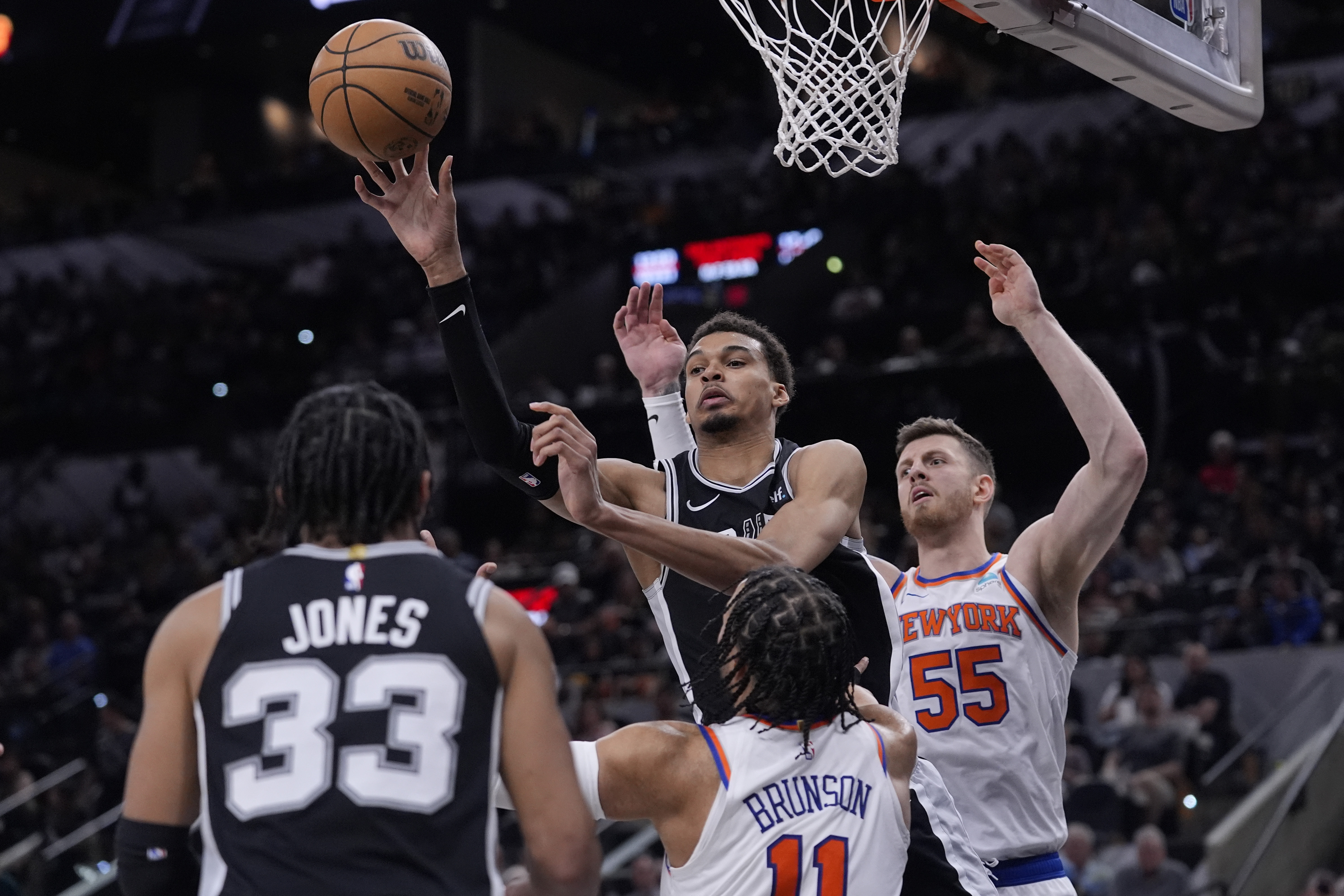 San Antonio Spurs center Victor Wembanyama, center, passes the ball over New York Knicks guard Jalen Brunson (11) during the second half of an NBA basketball game in San Antonio, Friday, March 29, 2024. 