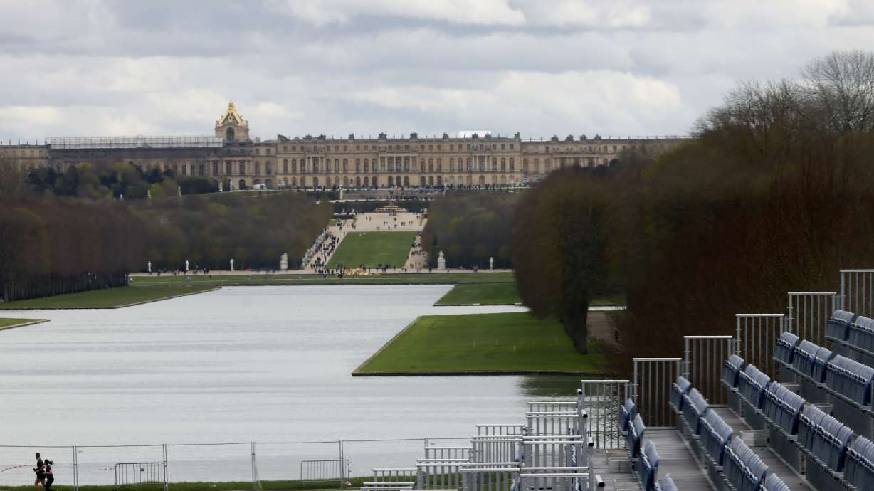A couple jogs past the stands to watch the equestrian sports, Friday, March 29, 2024 in the park of the Chateau de Versailles, west of Paris. The site will be the venue for equestrian sports at the Paris 2024 Olympic Games. The Chateau de Versailles is seen in background.