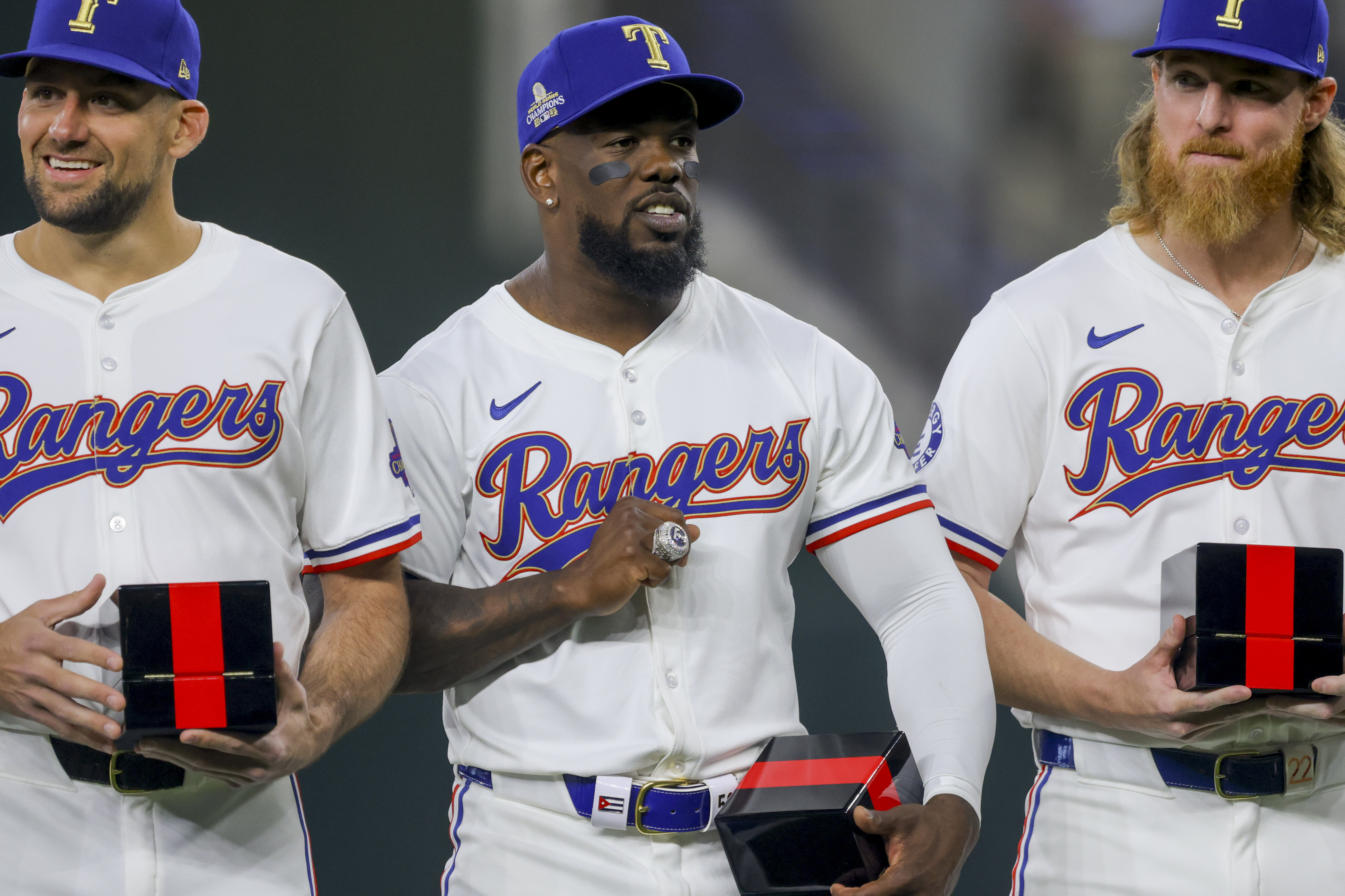 Texas Rangers players Nathan Eovaldi, left; Adolis Garcia, center; and Jon Gray, right, pose with their World Series rings before a baseball game against the Chicago Cubs, Saturday, March 30, 2024, in Arlington, Texas. 