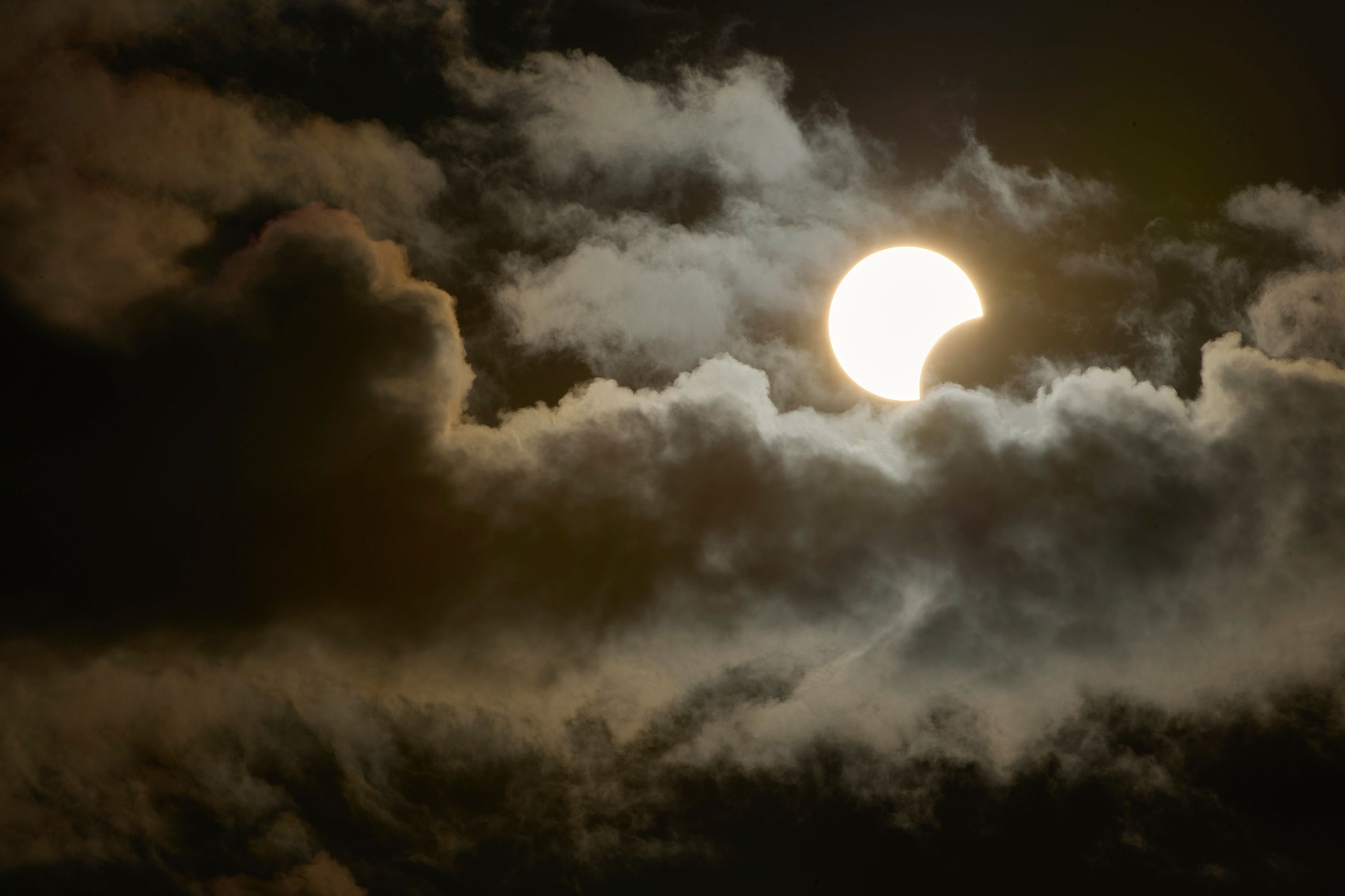 A partial solar eclipse is seen between clouds from Socorro in Sao Paulo, Brazil, on Oct. 14, 2023. When the total solar eclipse traces a path on April 8, spectators can anticipate a multitude of awe-inspiring moments.