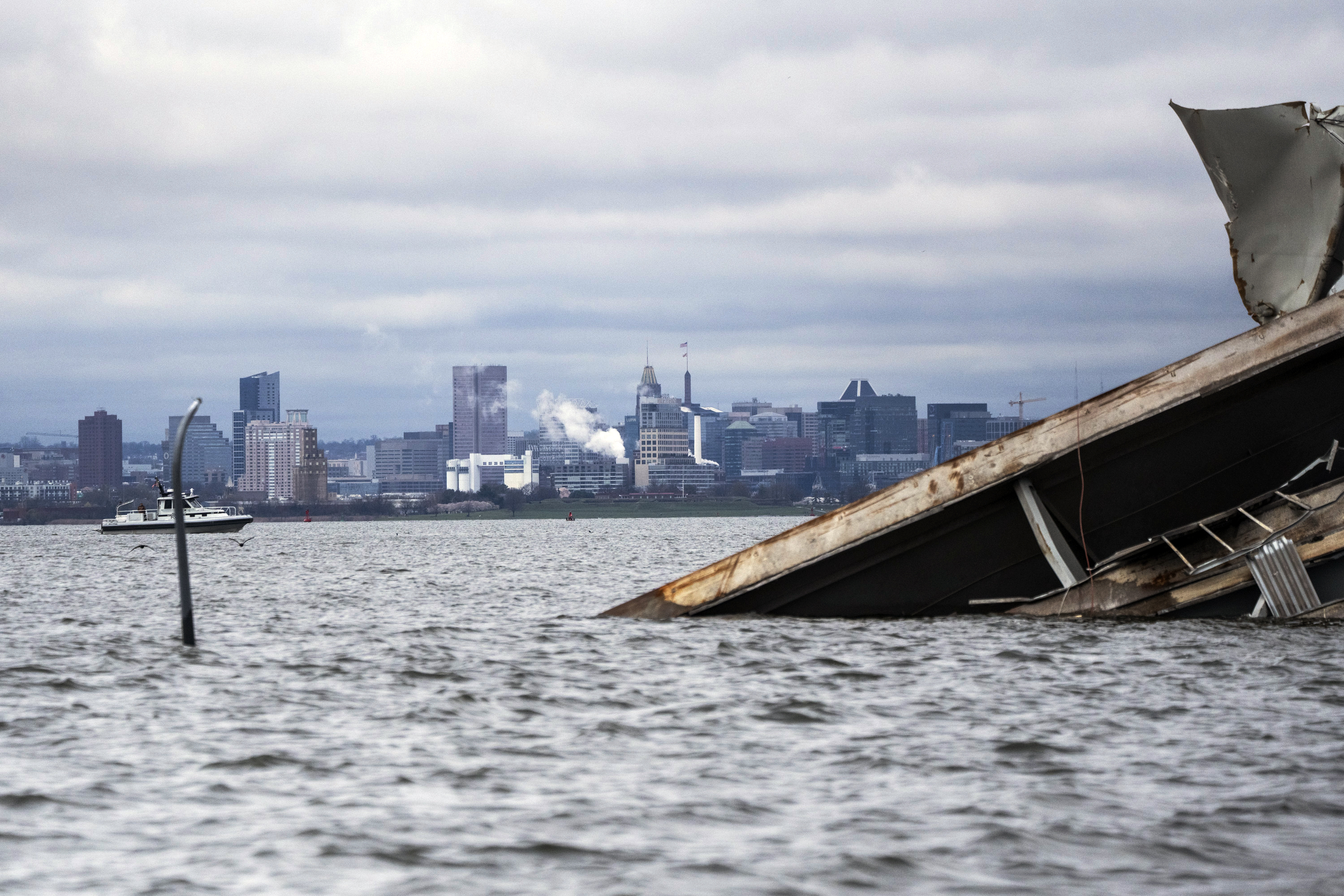 A section of the damaged and collapsed Francis Scott Key Bridge is seen, in the Baltimore port, Monday. A tugboat pushing a fuel barge has become the first vessel to use an alternate channel to bypass the wreckage.
