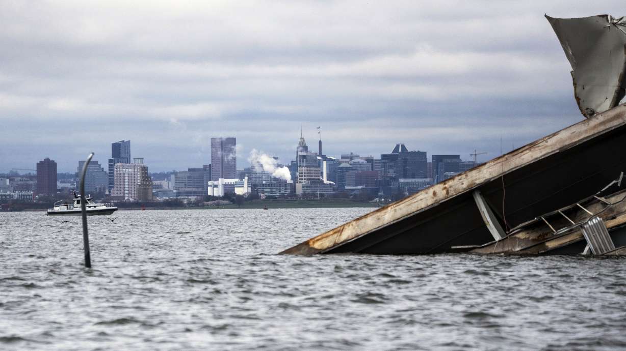 A section of the damaged and collapsed Francis Scott Key Bridge is seen, in the Baltimore port, Monday. A tugboat pushing a fuel barge has become the first vessel to use an alternate channel to bypass the wreckage.