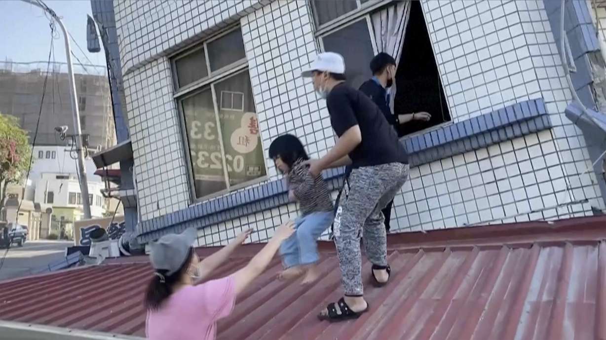 In this image taken from a video footage run by TVBS, residents rescue a child from a partially collapsed building in Hualien, eastern Taiwan on Wednesday.