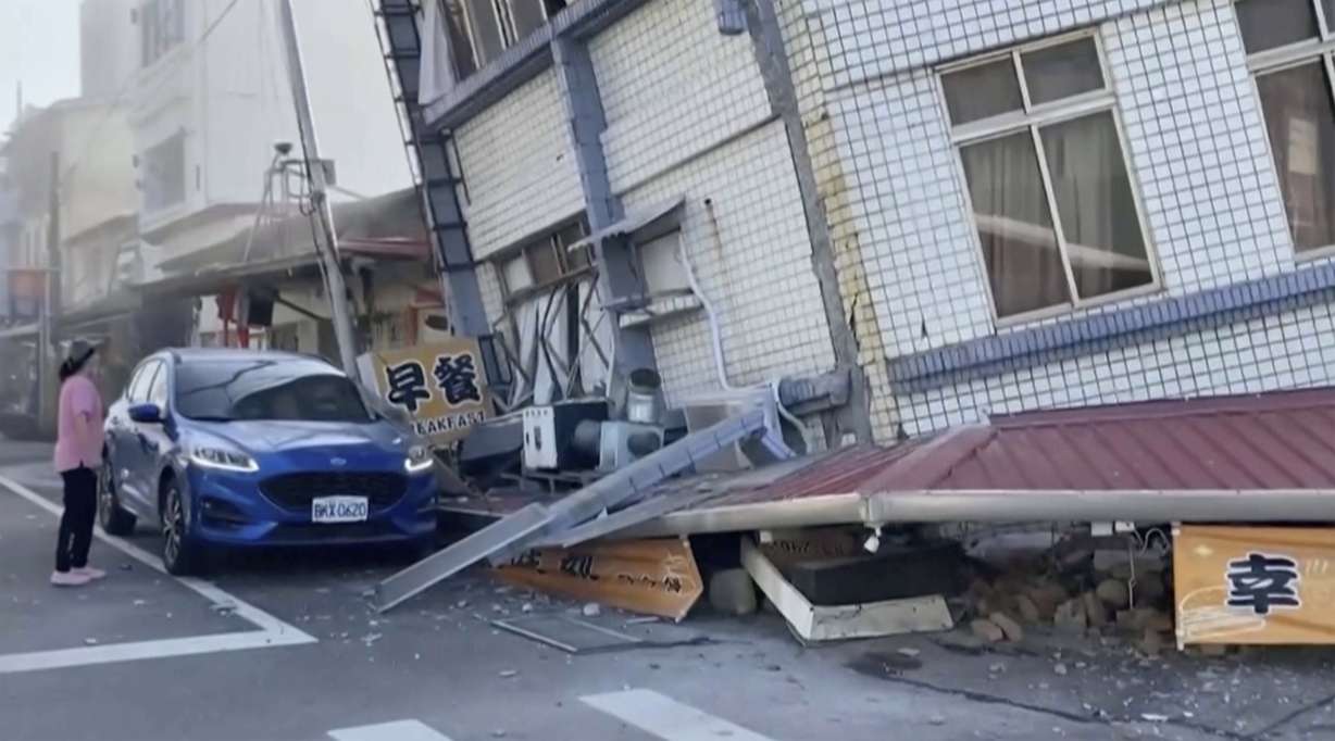 In this image taken from a video footage run by TVBS, a woman stands near a partially collapsed building in Hualien, eastern Taiwan on Wednesday.
