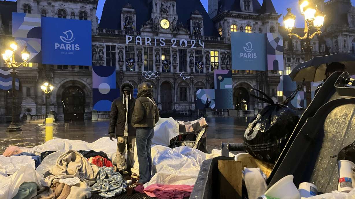 Migrants stand in front of the Paris City Hall, Wednesday, April 3, 2024. French police has removed about 50 migrants, including families with young children, from the Paris City Hall plaza as the capital prepares to mark 100 days to the start of the Olympic Games.