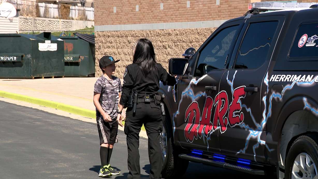 An officer lets fifth-grader Jaeden take a closer look at his design.