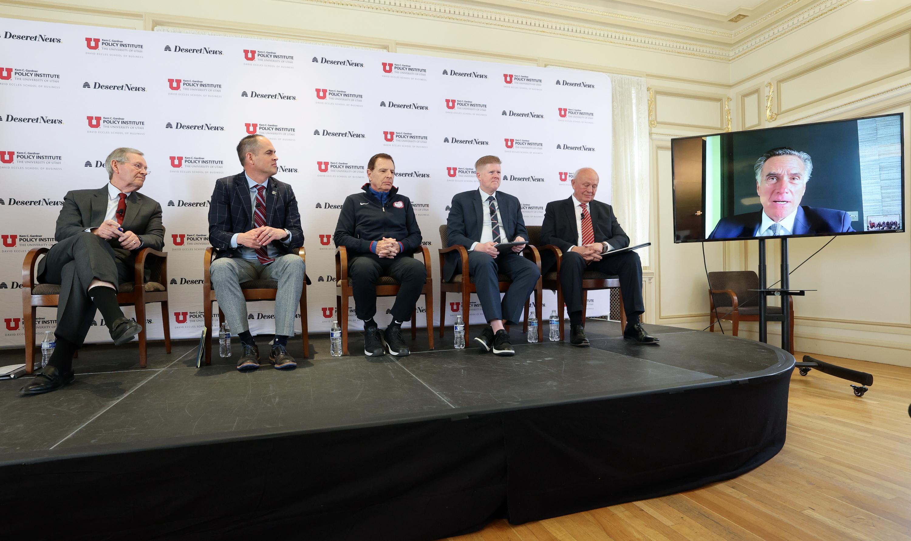 Former Gov. Michael O. Leavitt, Sen. Mike McKell, Fraser Bullock, Rep. Jon Hawkins, Lane Beattie, and Sen. Mitt Romney, via video, participate in a panel discussion about Olympic Games at the Thomas S. Monson Center in Salt Lake City on Friday.