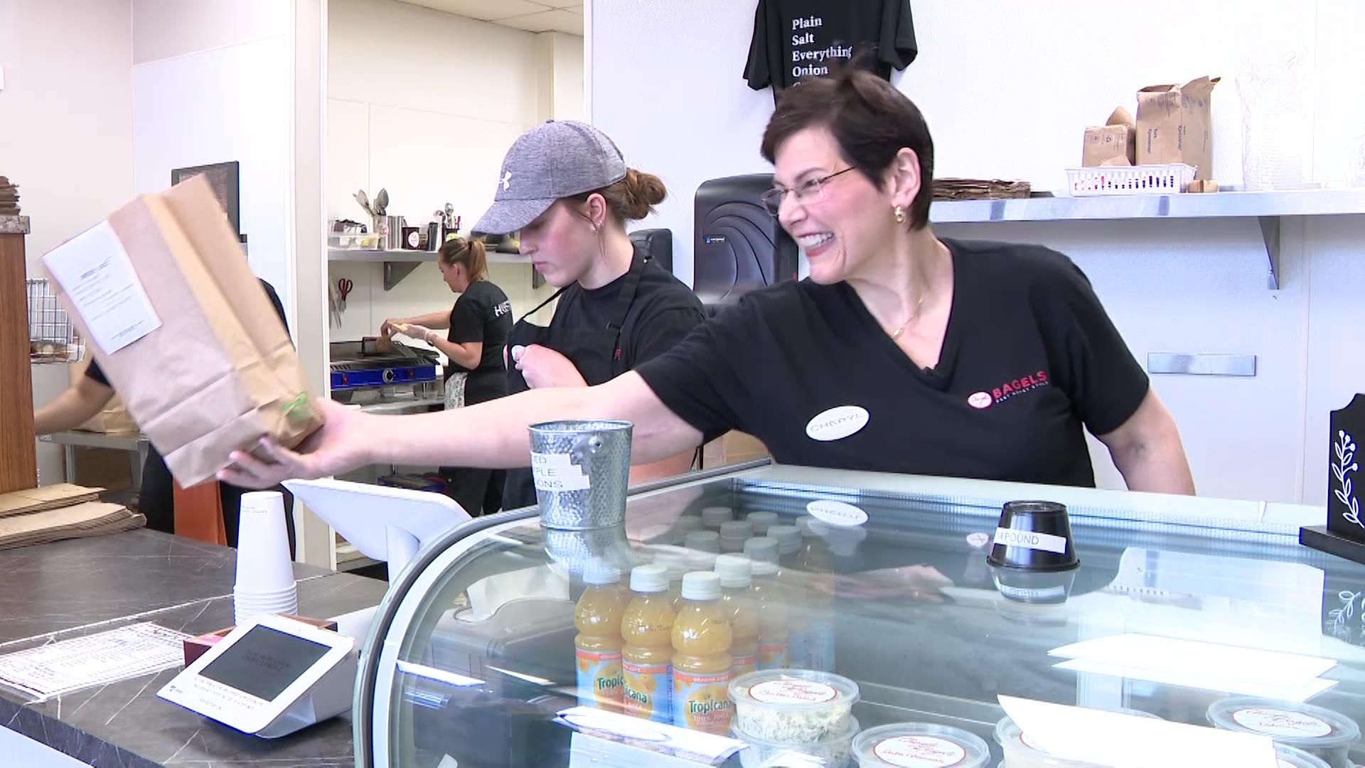 Cheryl Mignone works with her women-powered team at the register of her bagel shop.