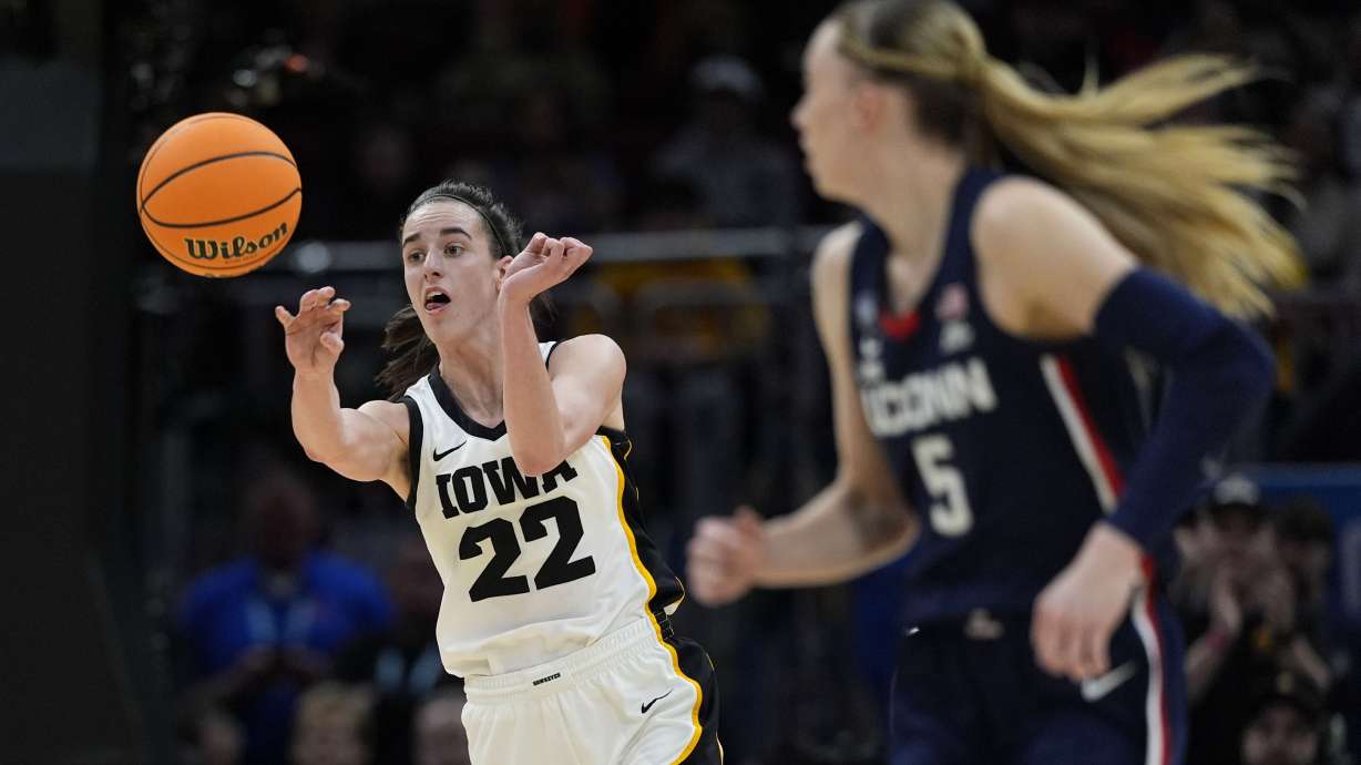 Iowa guard Caitlin Clark (22) passes up court in front of UConn guard Paige Bueckers (5) during the first half of a Final Four college basketball game in the women's NCAA Tournament, Friday, April 5, 2024, in Cleveland.