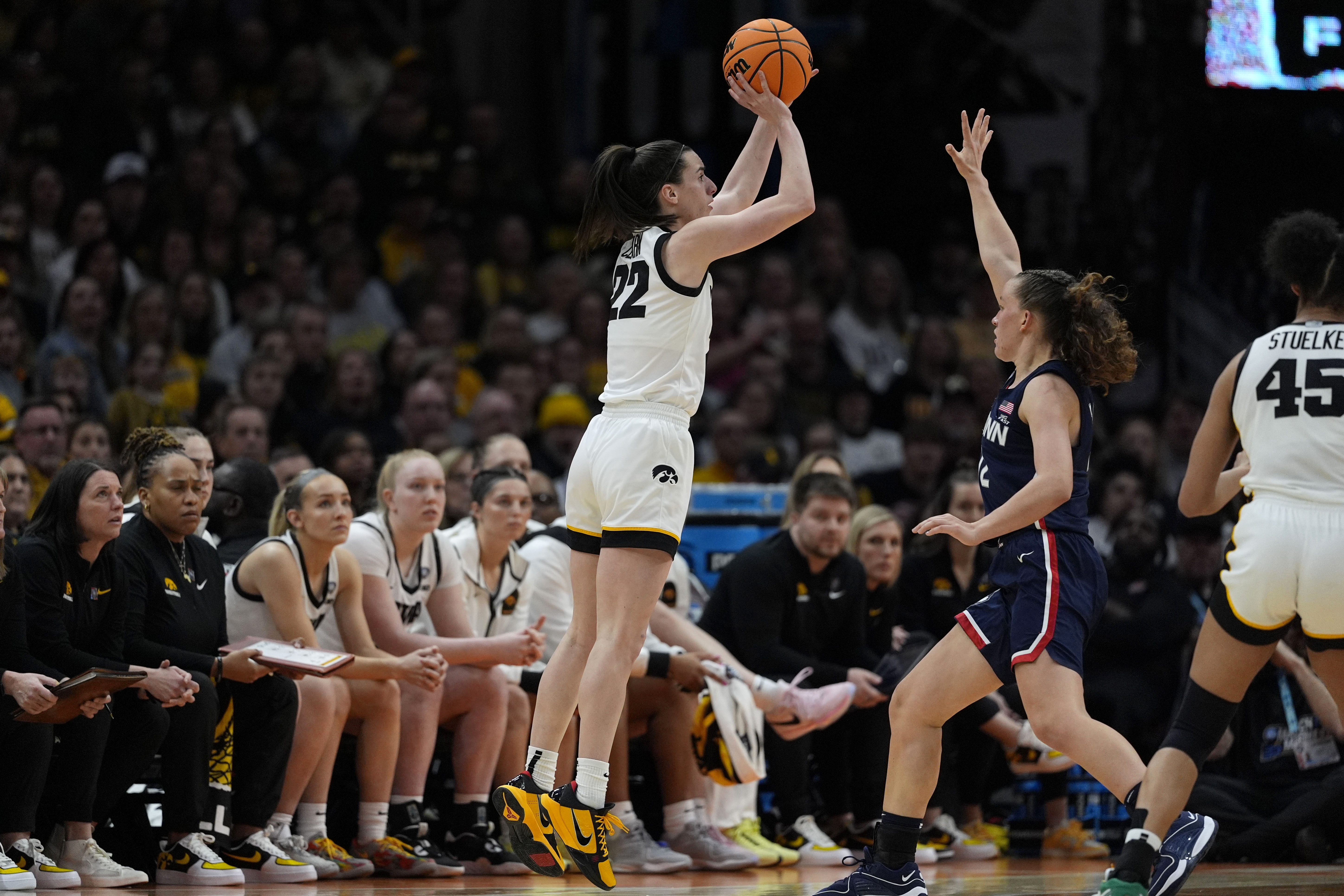 Iowa guard Caitlin Clark (22) shoots a three-point basket over UConn guard Ashlynn Shade, right, during the second half of a Final Four college basketball game in the women's NCAA Tournament, Friday, April 5, 2024, in Cleveland. 