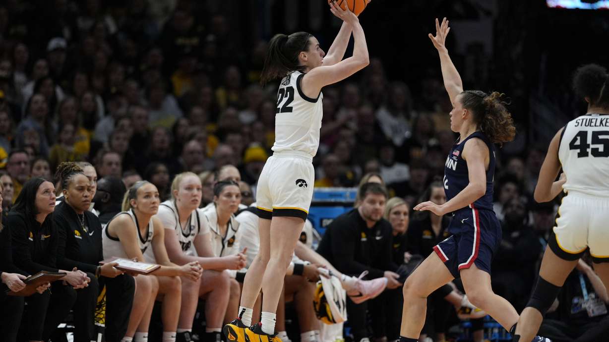 Iowa guard Caitlin Clark (22) shoots a three-point basket over UConn guard Ashlynn Shade, right, during the second half of a Final Four college basketball game in the women's NCAA Tournament, Friday, April 5, 2024, in Cleveland.