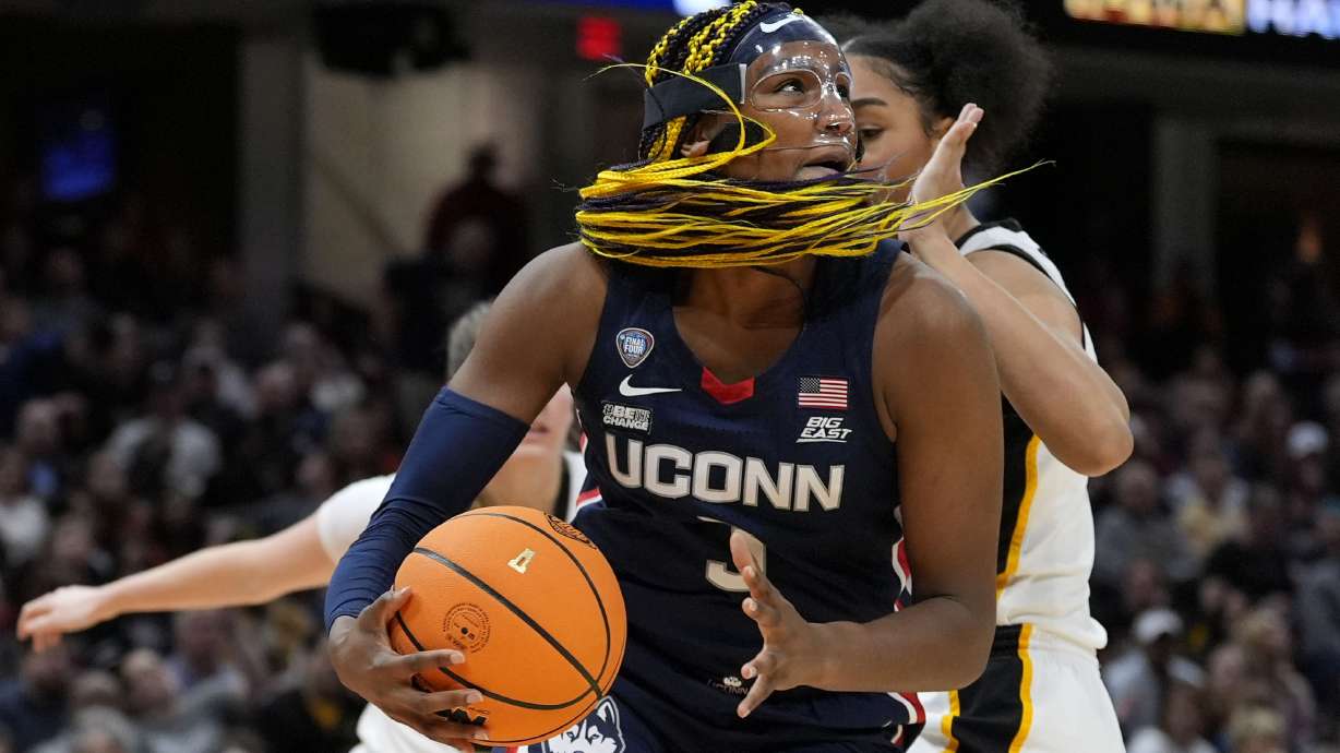 UConn forward Aaliyah Edwards drives to the basket in front of Iowa forward Hannah Stuelke, rear, during the first half of a Final Four college basketball game in the women's NCAA Tournament, Friday, April 5, 2024, in Cleveland.