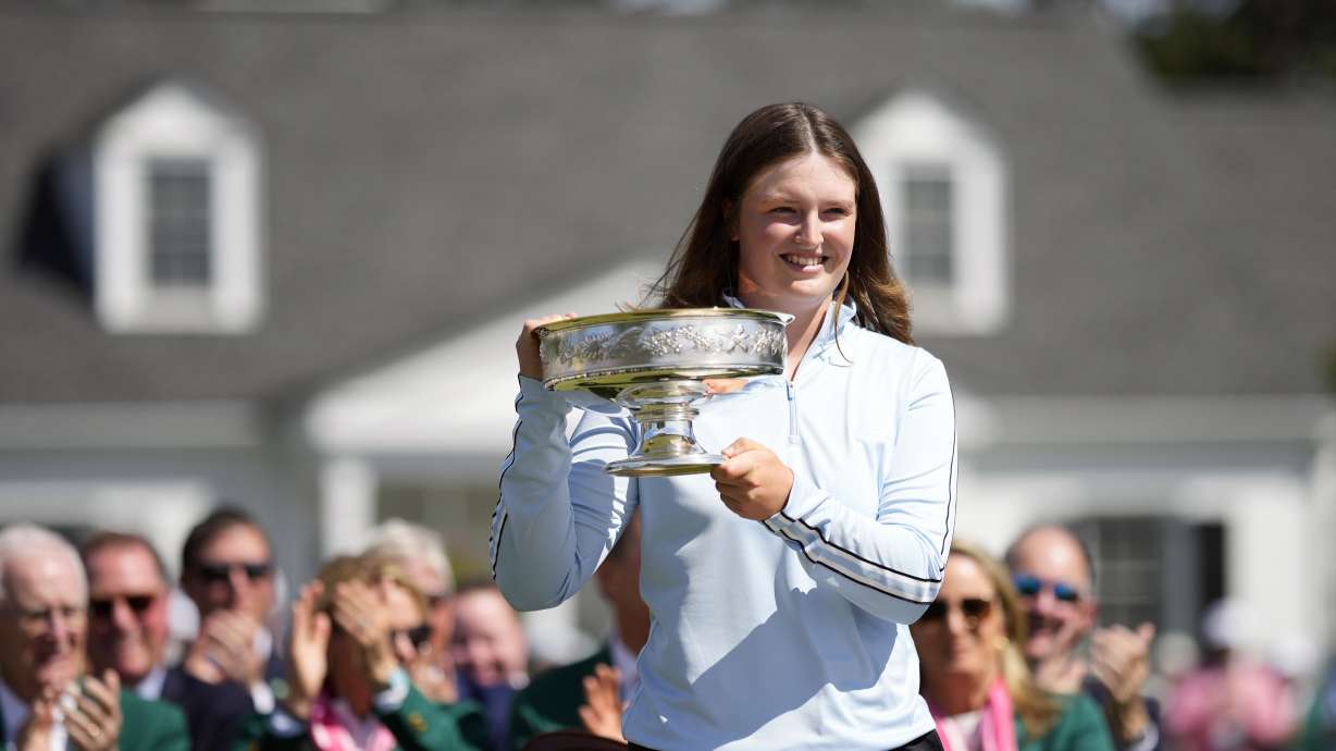 Lottie Woad, of England, poses with the trophy for photographers after winning the Augusta National Women's Amateur golf tournament, Saturday, April 6, 2024, in Augusta, Ga.