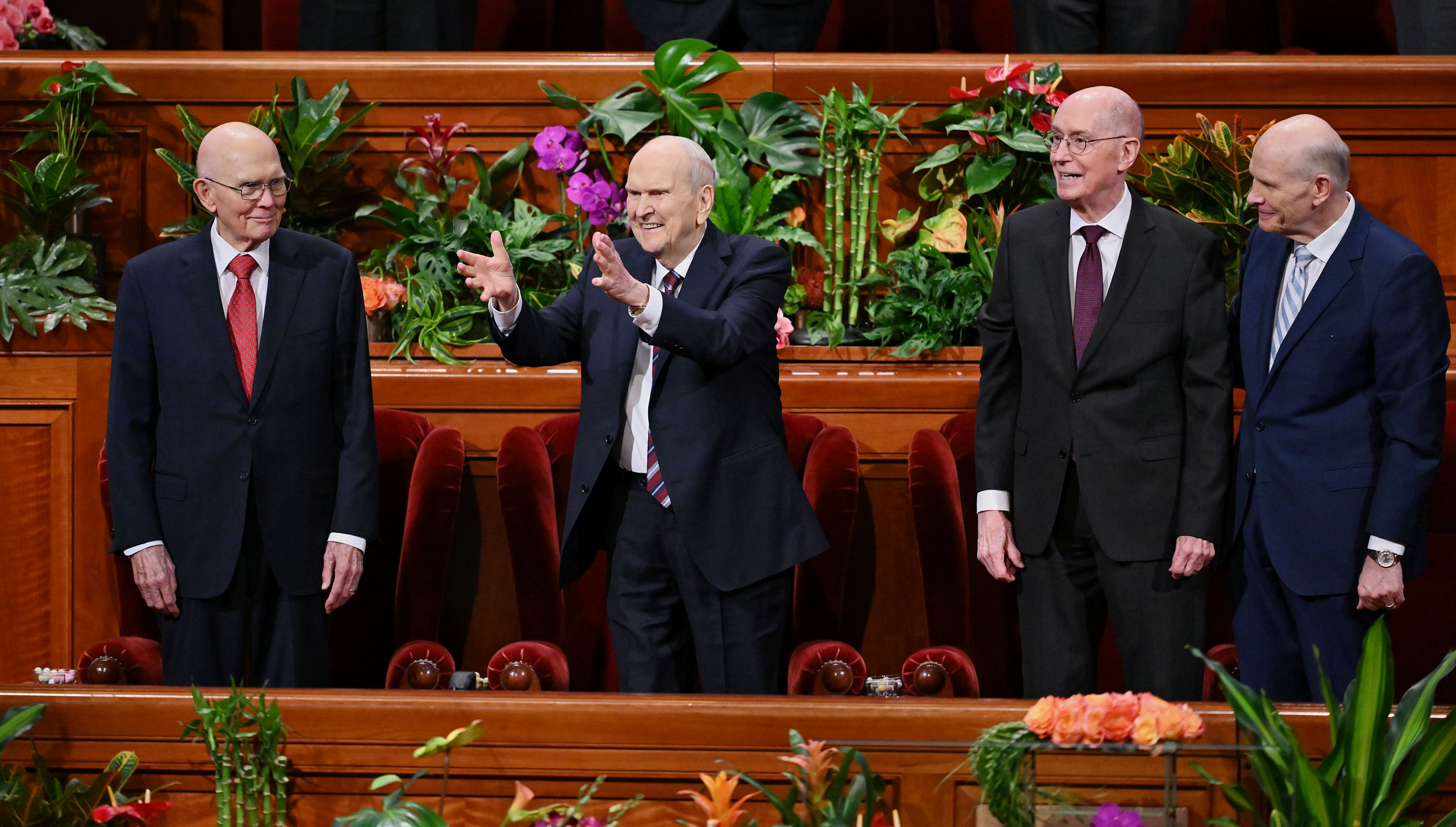 President Russell M. Nelson holds his hands out and gestures toward the audience as he and his counselors, President Dallin H. Oaks, first counselor in the First Presidency, left, and President Henry B. Eyring, second counselor, take their seats prior to the afternoon session of general conference in Salt Lake City on Sunday.