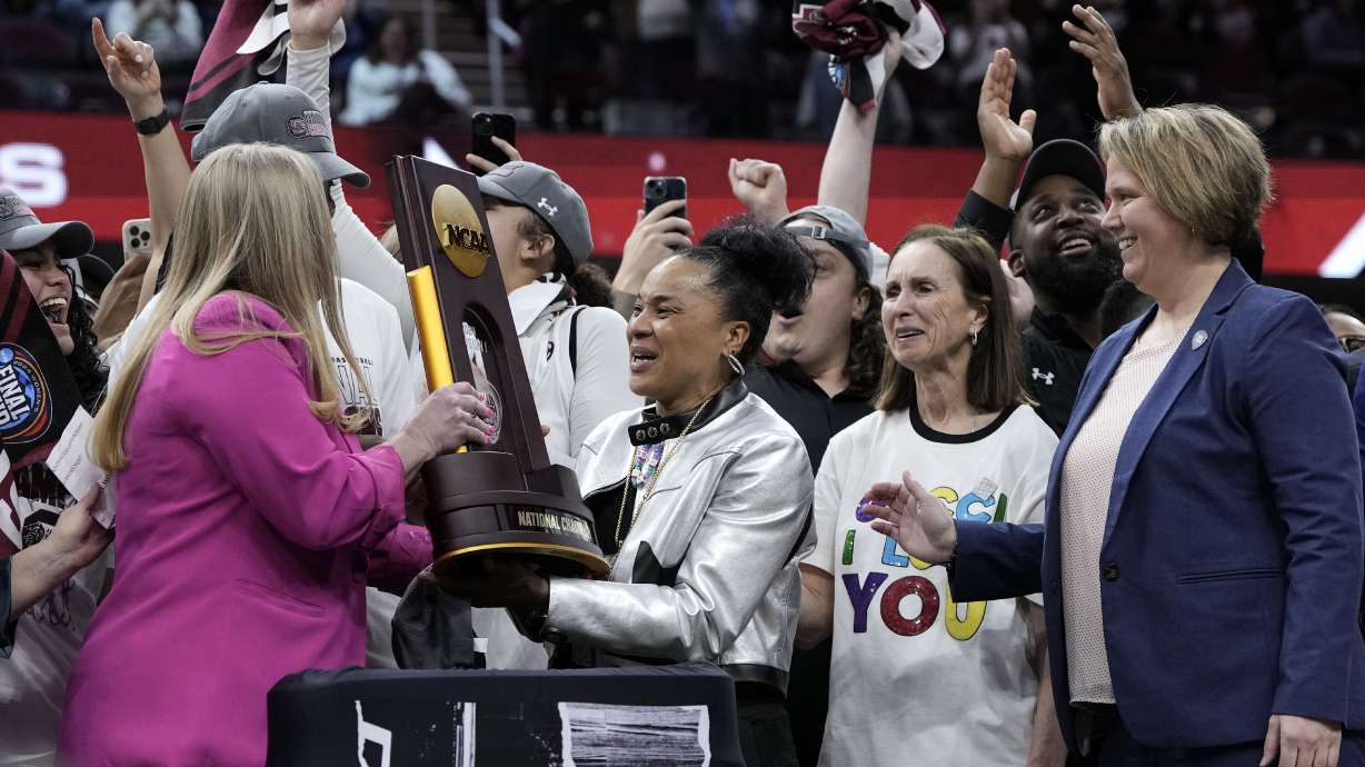 South Carolina head coach Dawn Staley, center, celebrates with the trophy after the Final Four college basketball championship game against Iowa in the women's NCAA Tournament, Sunday, April 7, 2024, in Cleveland. South Carolina won 87-75.