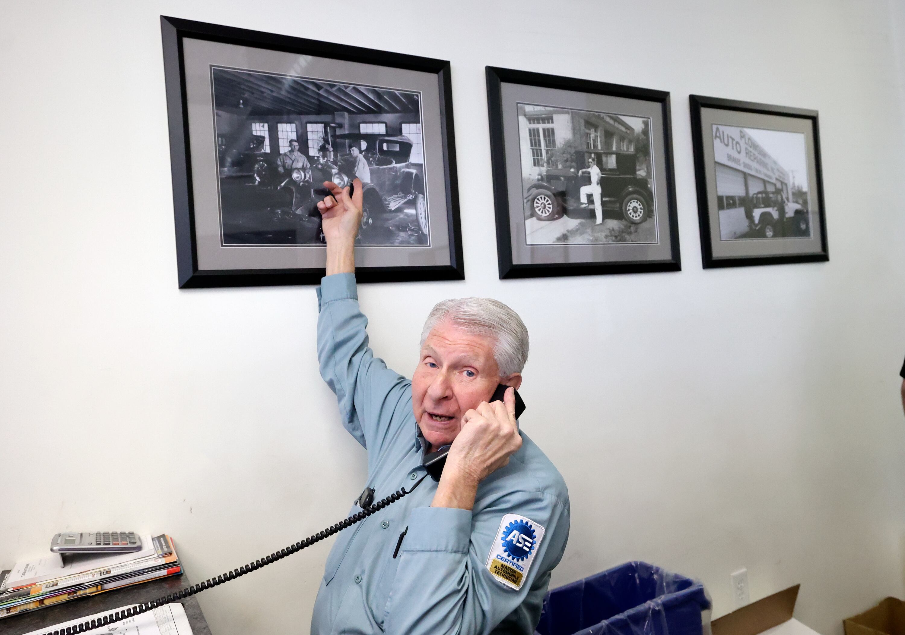 Larry Plowgian points out a historical photo of his grandfather and his grandfather’s brother-in-law working at Plowgian Auto Repair in Sugar House in 1928, which now hangs in the new location of Plowgian Auto Repair in Millcreek on March 18. Larry is the third of five generations that have worked at Plowgian Auto Repair.