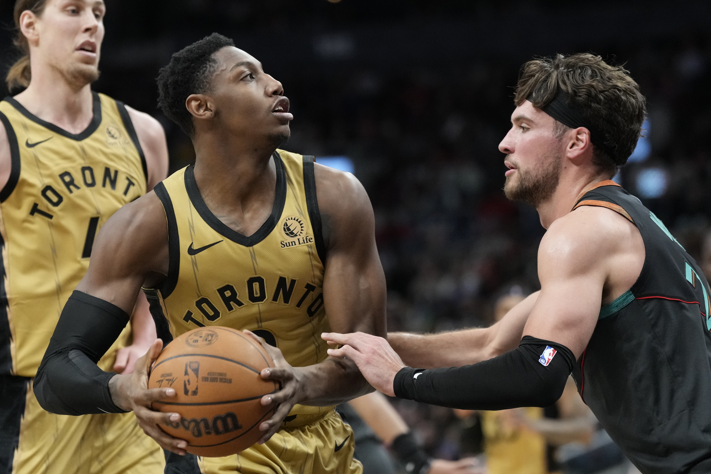 Toronto Raptors guard RJ Barrett, center, controls the ball and looks towards the basket as Washington Wizards forward Corey Kispert defends during the first half of an NBA basketball game in Toronto on Sunday, April 7, 2024. 