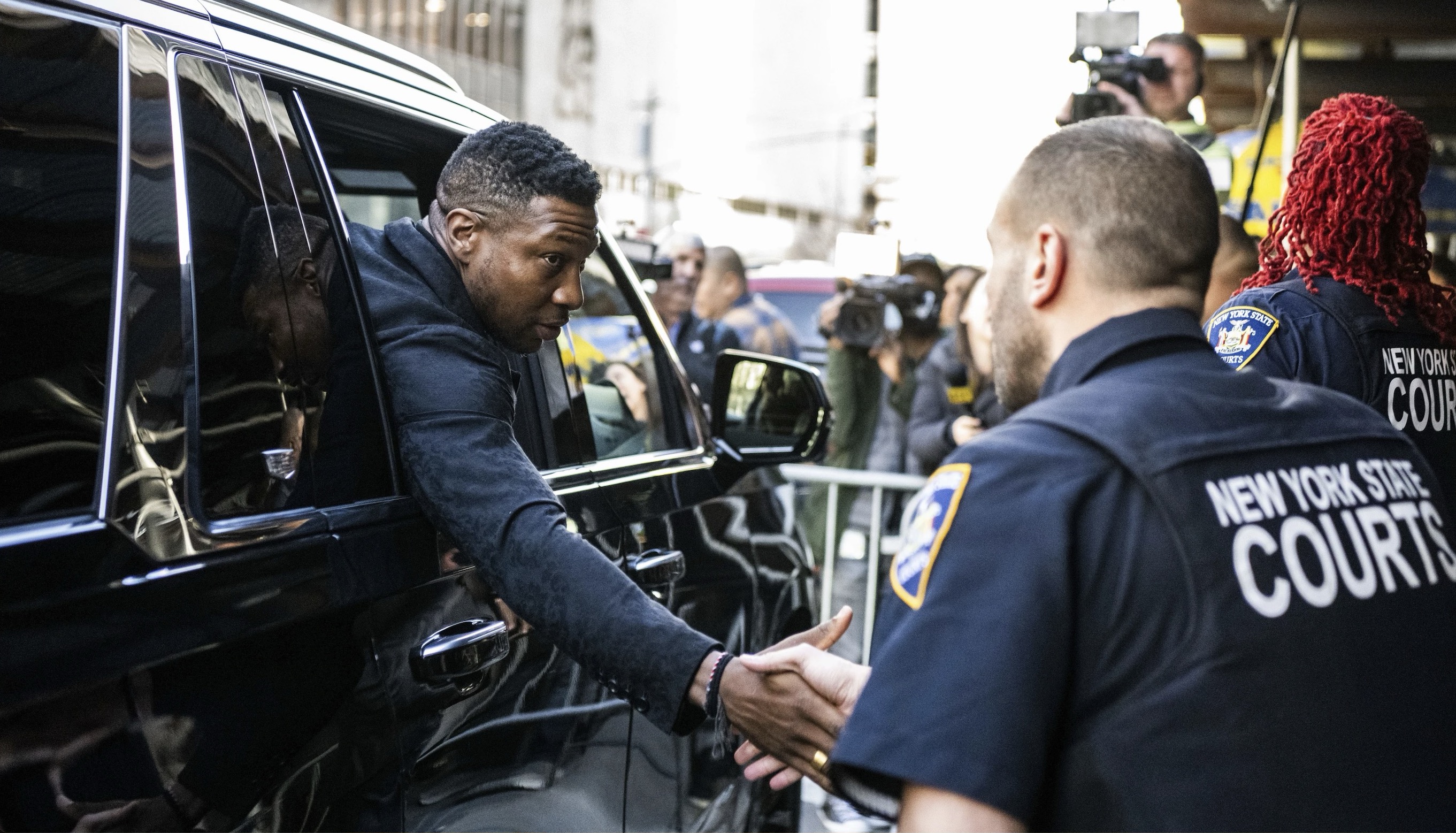 Actor Jonathan Majors shakes hands with court police officers on Monday in New York after his sentencing for assaulting Grace Jabbari.