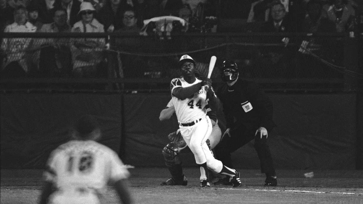 FILE - Atlanta Braves' Hank Aaron eyes the flight of the ball after hitting his 715th career homer in a game against the Los Angeles Dodgers in Atlanta, Ga., Monday night, April 8, 1974. Aaron broke Babe Ruth's record of 714 career home runs. Dodgers southpaw pitcher Al Downing, catcher Joe Ferguson and umpire David Davidson look on. Just in time for the 50-year anniversary of Hank Aaron's record 715th home run, Charlie Russo is making available video he shot of the homer.