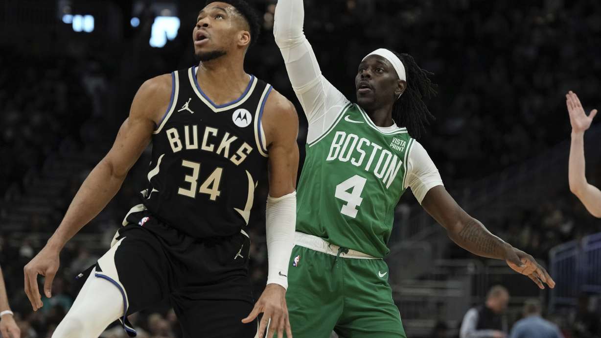 Boston Celtics' Jrue Holiday watches his shot with Milwaukee Bucks' Giannis Antetokounmpo during the first half of an NBA basketball game Tuesday, April 9, 2024, in Milwaukee.