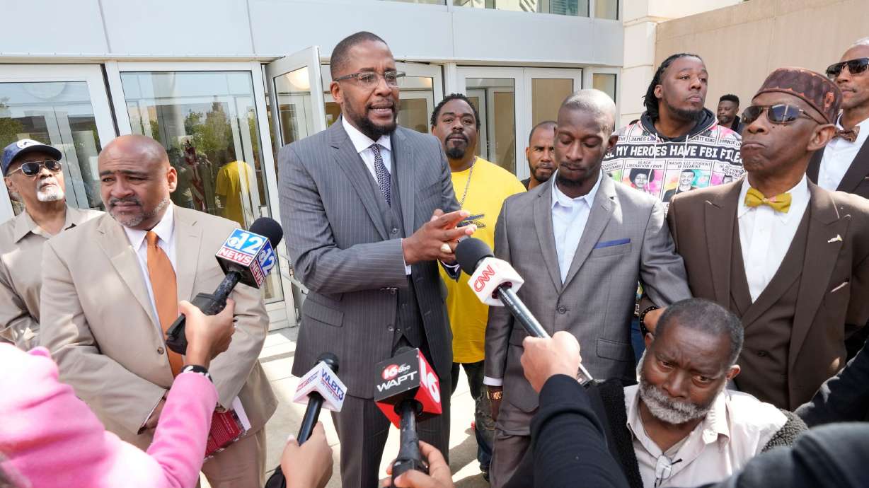 Attorney Malik Shabazz, center, speaks outside the federal courthouse in Jackson, Miss., after a sentencing hearing in March as his client, Michael Jenkins, listens.