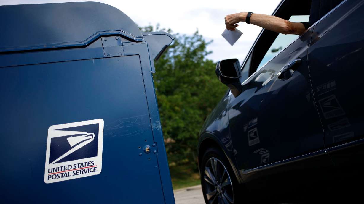 A motorist drops a letter into a USPS mail drop box at a post office in Kentucky in 2022. Stamp prices are set to increase.