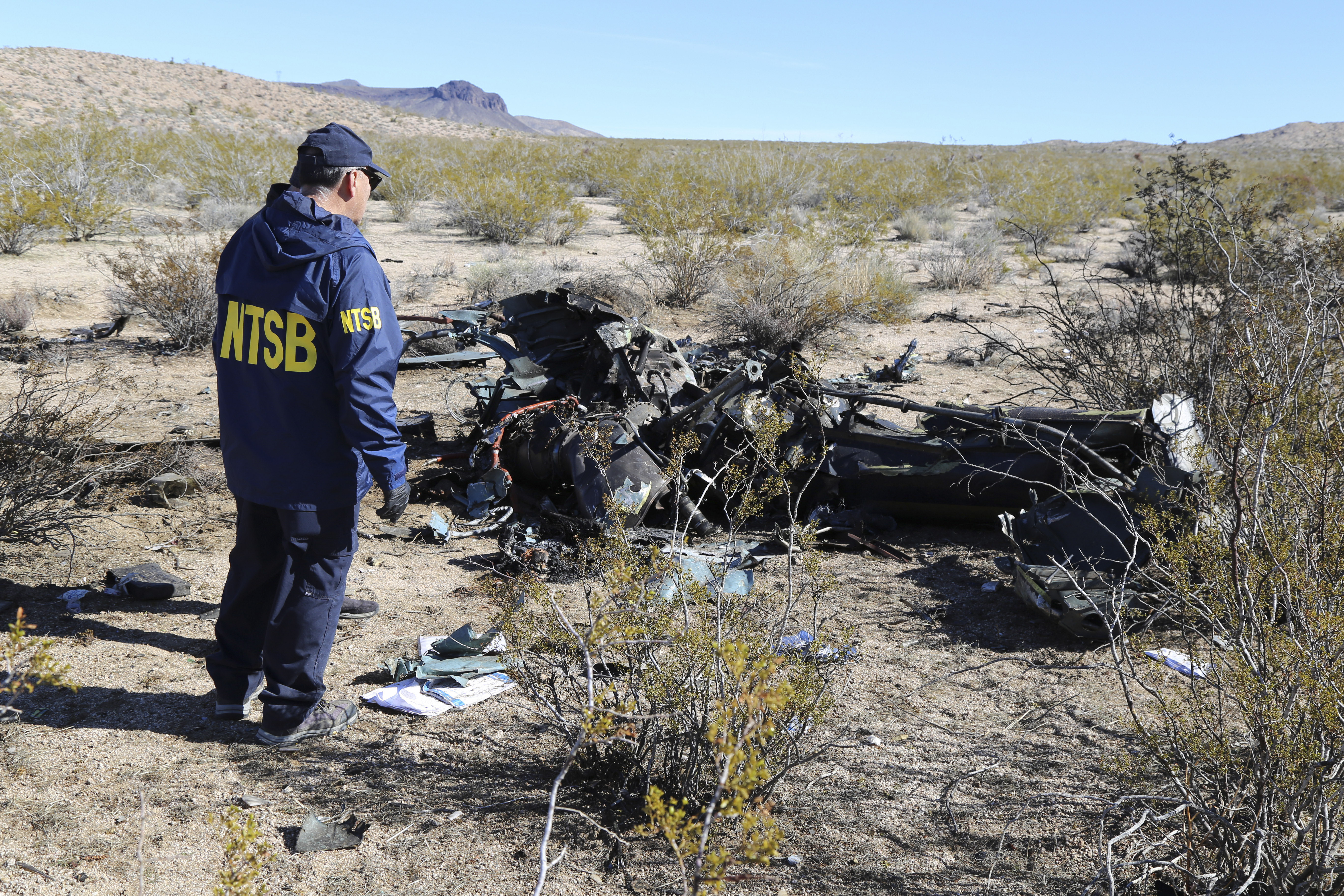 FILE - In this photo provided by the National Transportation Safety Board, an NTSB investigator surveys the site of an Airbus Helicopters EC-130 on Sunday, Feb. 11, 2024, near Halloran Springs, Calif. The family of a Nigerian business leader who died in the Southern California helicopter crash that killed five others filed a lawsuit Wednesday, April 10, claiming the flight should have been grounded because of treacherous weather. 