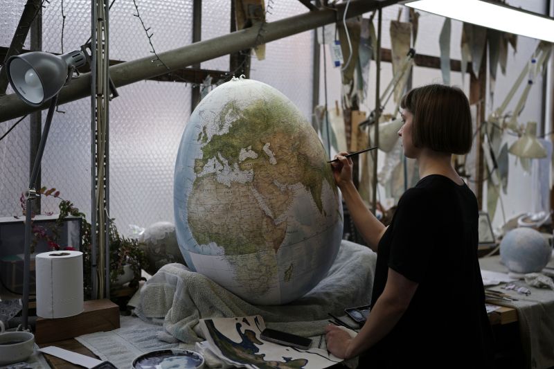 An artist paints a globe at a studio in London, Feb. 27.