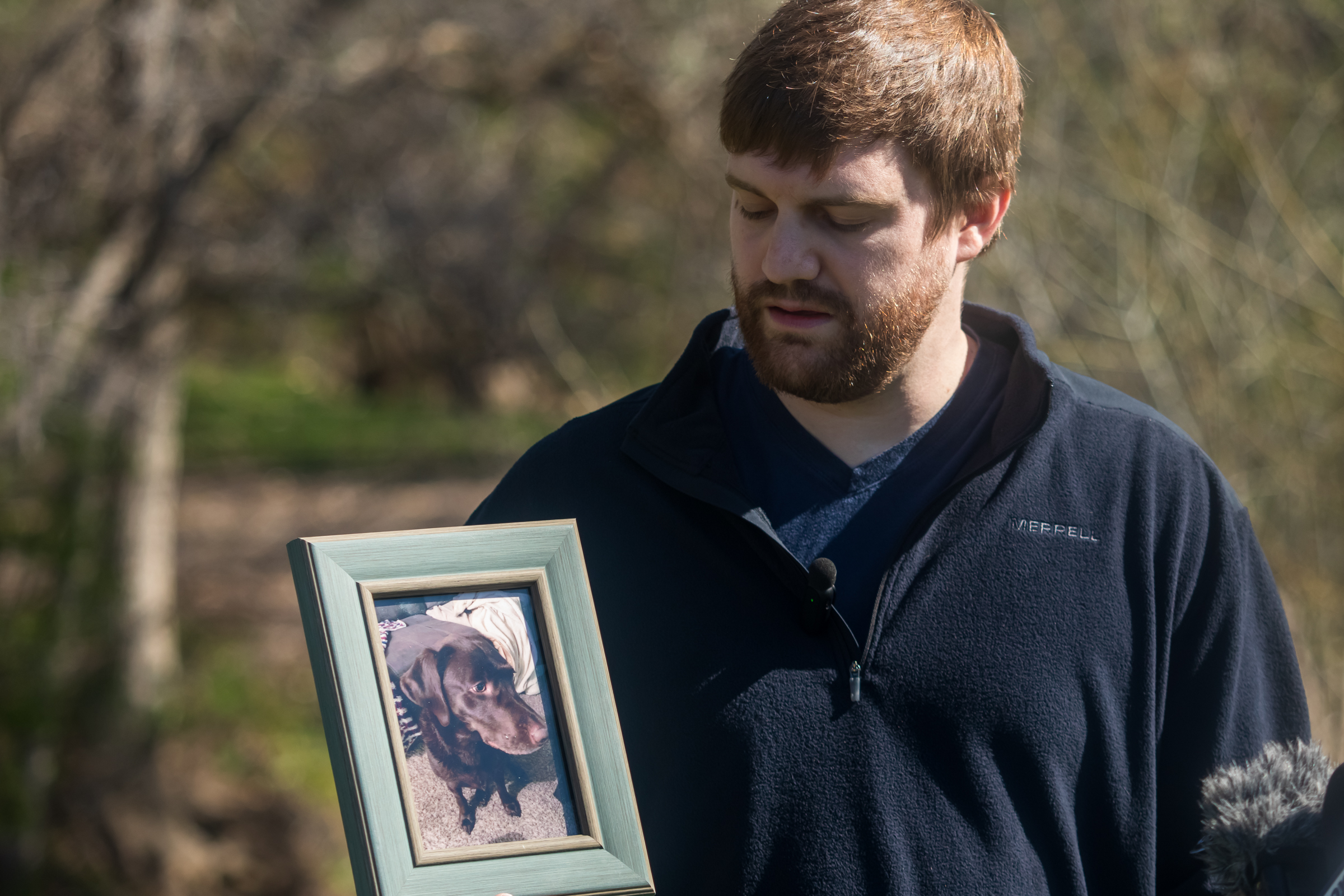 Travis Mundt, of West Jordan, stares at a framed photo of his dog Oliver at Sugar House Park on Friday. Oliver was swept away in Parleys Creek last year and never found.