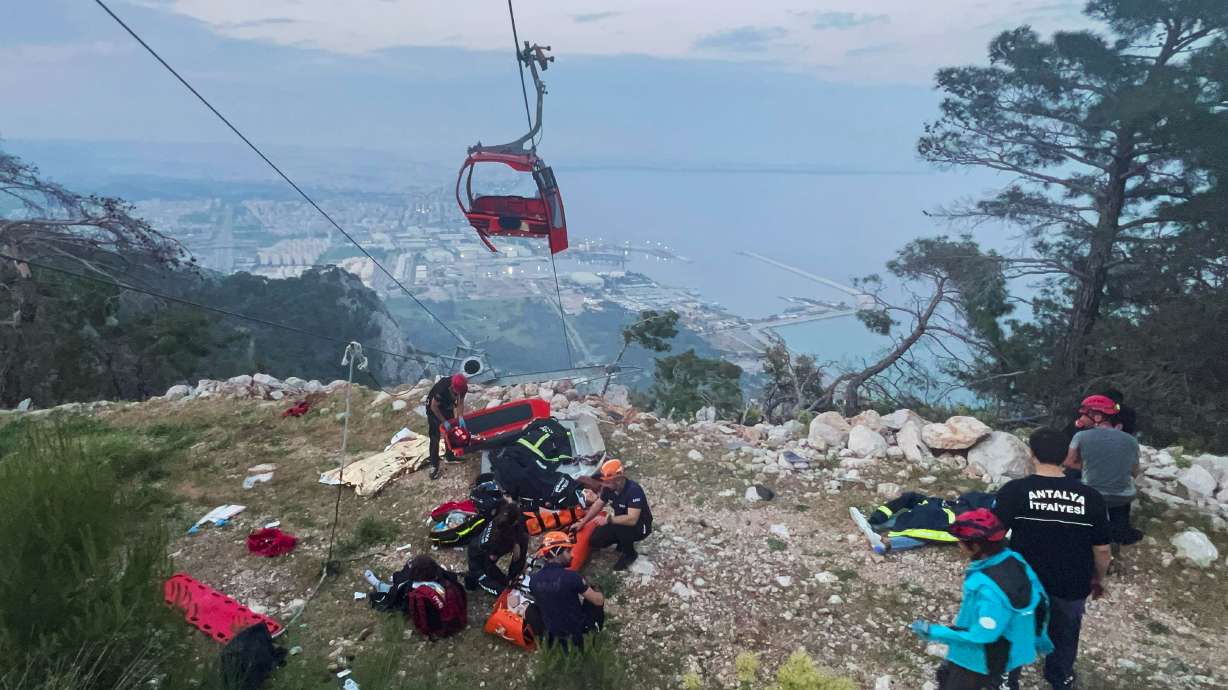 Rescue and emergency team members work with passengers of a cable car transportation system outside Antalya in Turkey on Friday. At least one person was killed and several injured Friday when a cable car pod hit a pole and burst open.