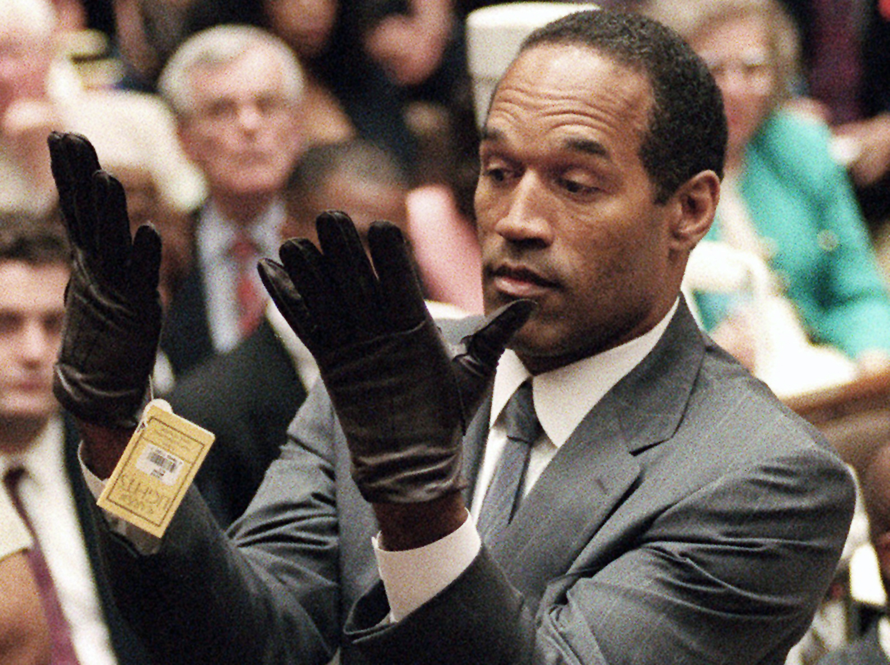 FILE - In this June 21, 1995 file photo, O.J. Simpson holds up his hands before the jury after putting on a new pair of gloves similar to the infamous bloody gloves during his double-murder trial in Los Angeles. Simpson, the decorated football superstar and Hollywood actor who was acquitted of charges he killed his former wife and her friend but later found liable in a separate civil trial, has died. He was 76.