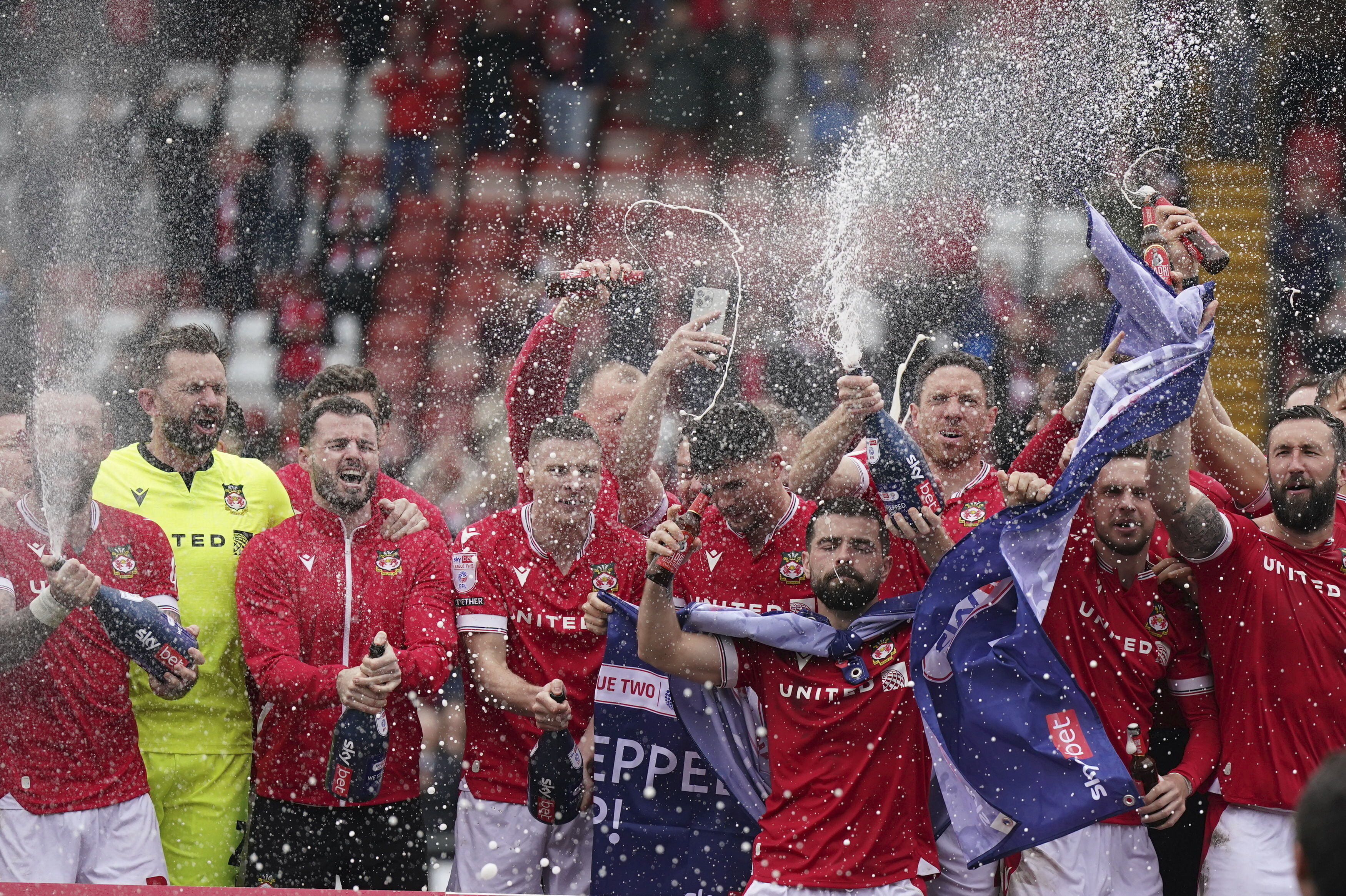 Wrexham players on the pitch celebrate promotion to League One after the final whistle of the Sky Bet League Two match at the SToK Cae Ras, Wrexham, Saturday April 13, 2024. 