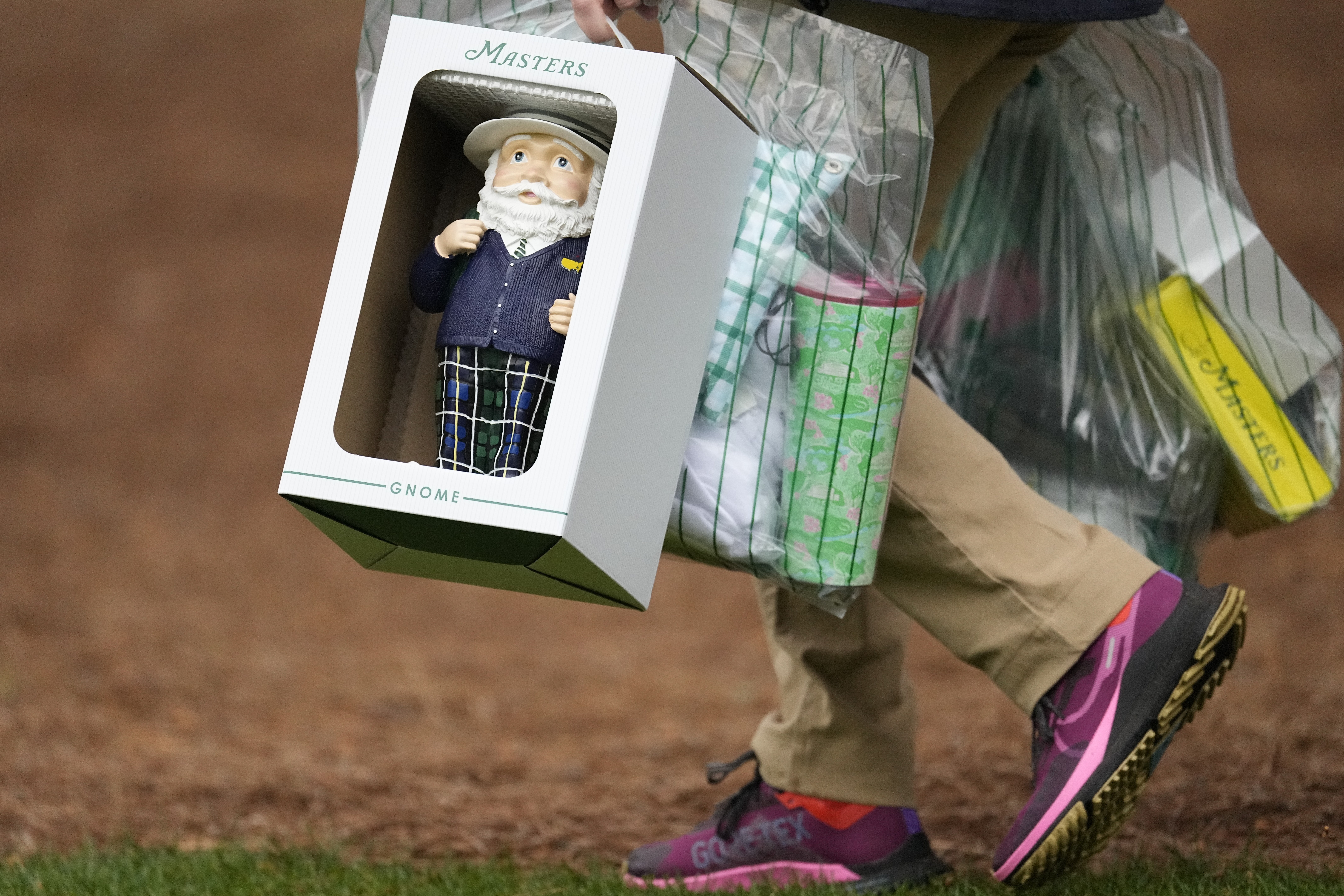 A patron carries a Masters gnome, a one-foot high ceramic figurine, during a practice round in preparation for the Masters golf tournament at Augusta National Golf Club Tuesday, April 9, 2024, in Augusta, Ga.