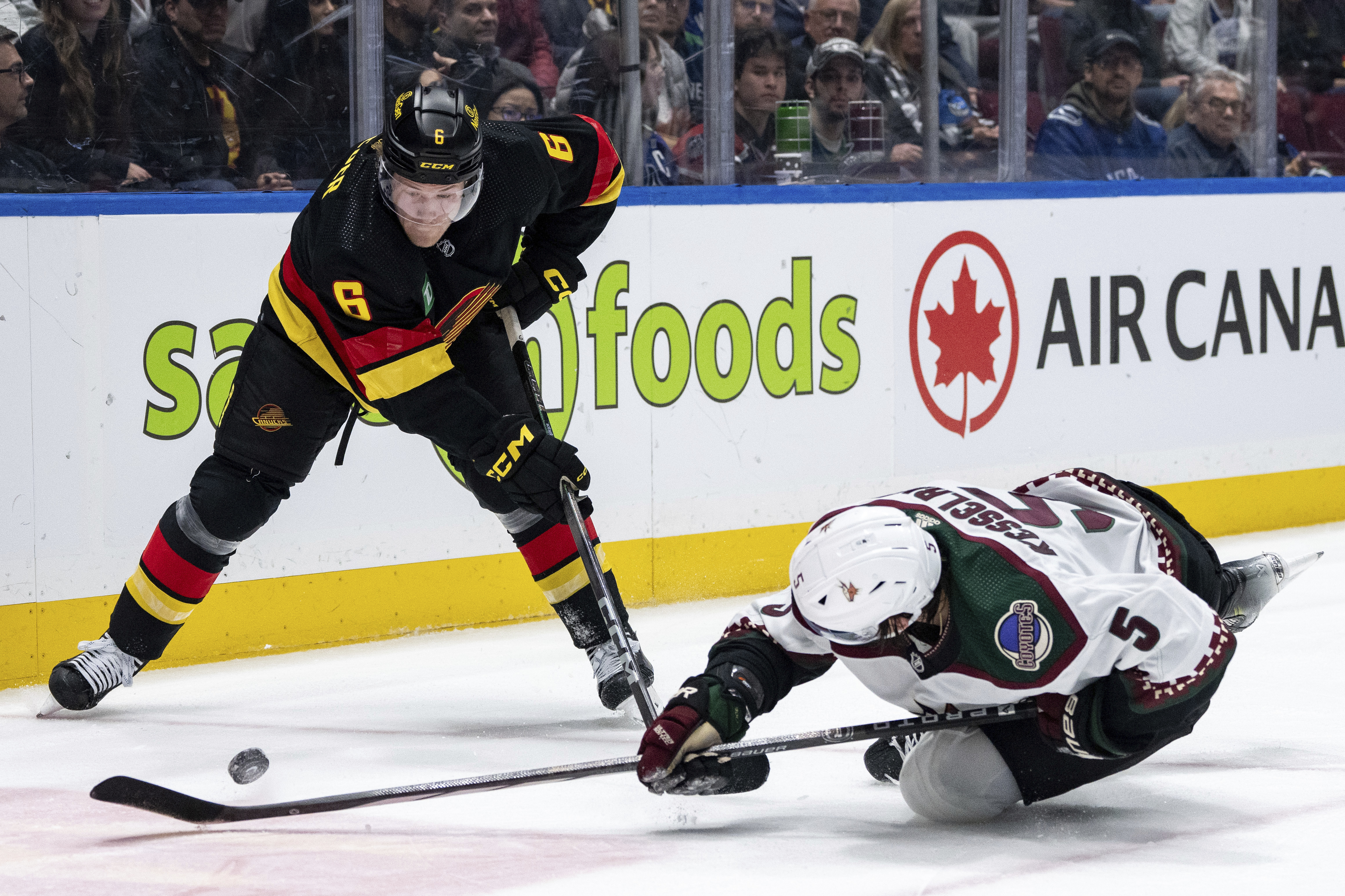 Vancouver Canucks' Brock Boeser (6) and Arizona Coyotes' Michael Kesselring (5) vie for the puck during the third period of an NHL hockey game Wednesday, April 10, 2024, in Vancouver, British Columbia.