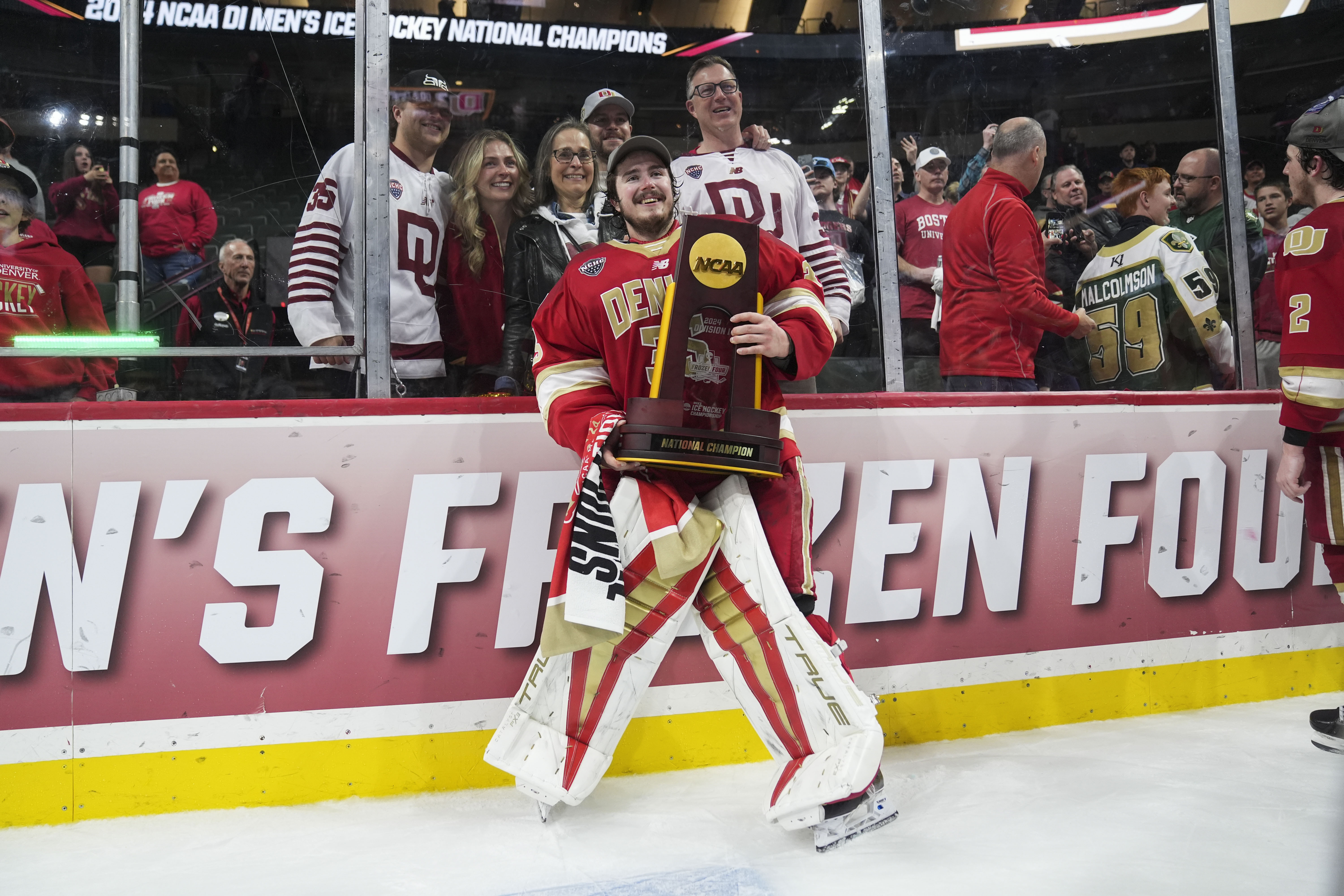 Denver goaltender Matt Davis (35) poses with the championship trophy, with his family behind him, after defeating Boston College in the championship game of the Frozen Four NCAA college hockey tournament Saturday, April 13, 2024, in St. Paul, Minn. Denver won 2-0 to win the national championship.