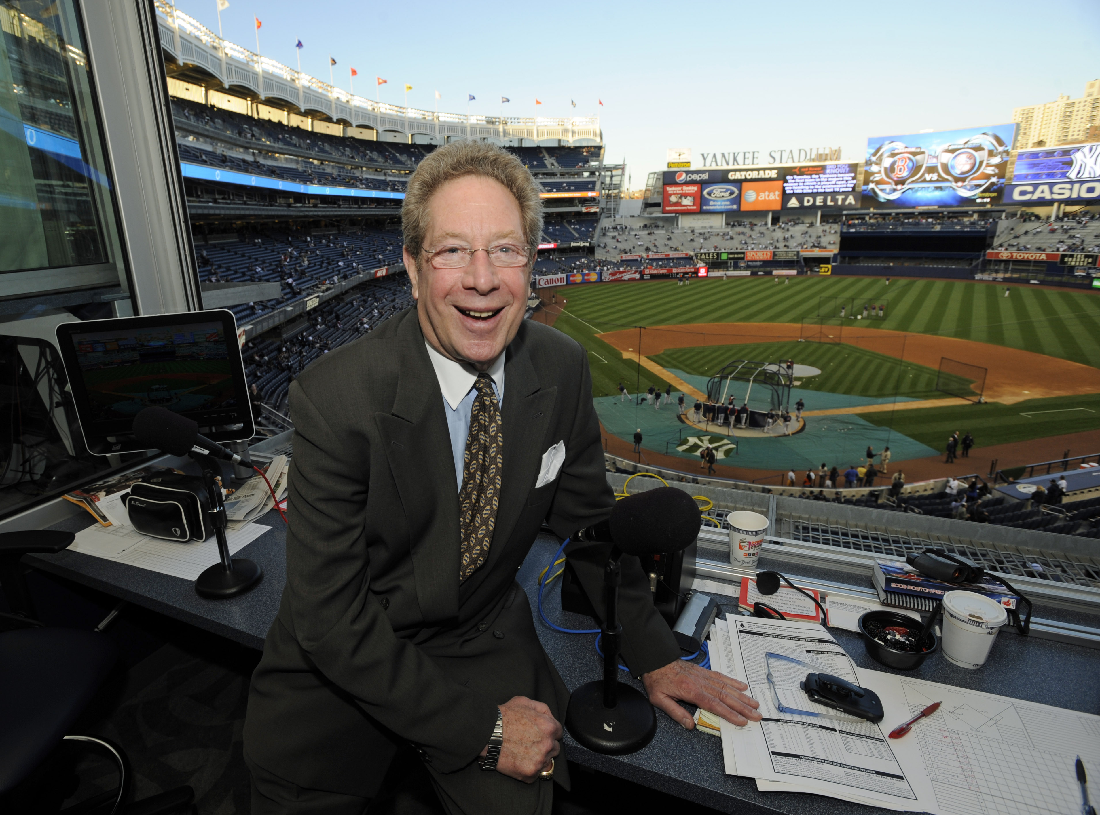 FILE - New York Yankees broadcaster John Sterling sits in his booth before a baseball game against the Boston Red Sox at Yankee Stadium in New York, Sept. 25, 2009. Sterling announced his immediate retirement Monday, April 15, 2024, at age 85 a few weeks into his 34th season in New York's broadcast booth. 