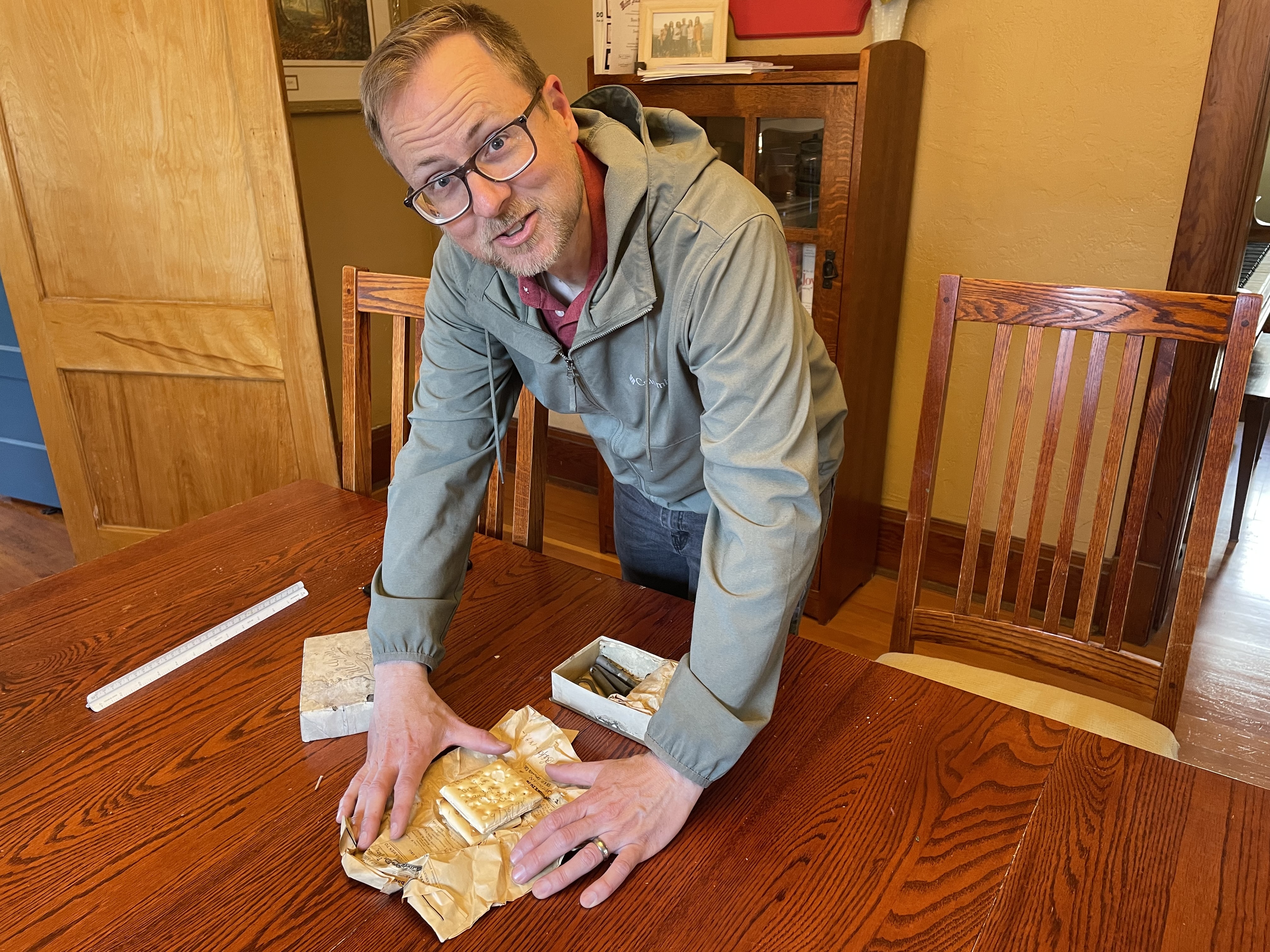 Jeremy Peterson found some items stuffed above the ceiling in an Ogden home he's renovating that he thinks are linked to the Spanish-American War. He's pictured here at his home with the items, which include a piece of hardtack with writing on it, on April 11, 2024.
